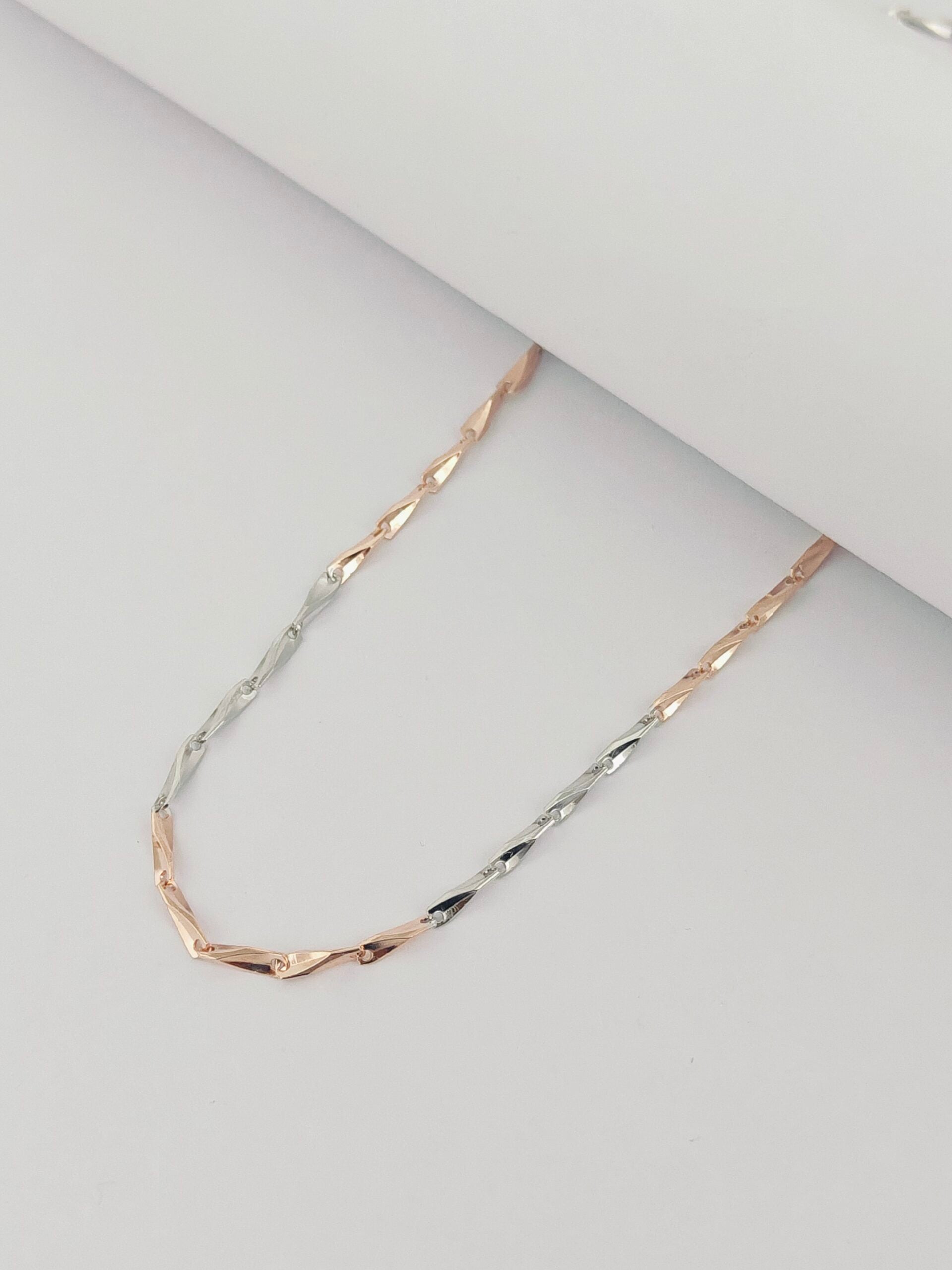 Two-tone gold necklace on a light gray background