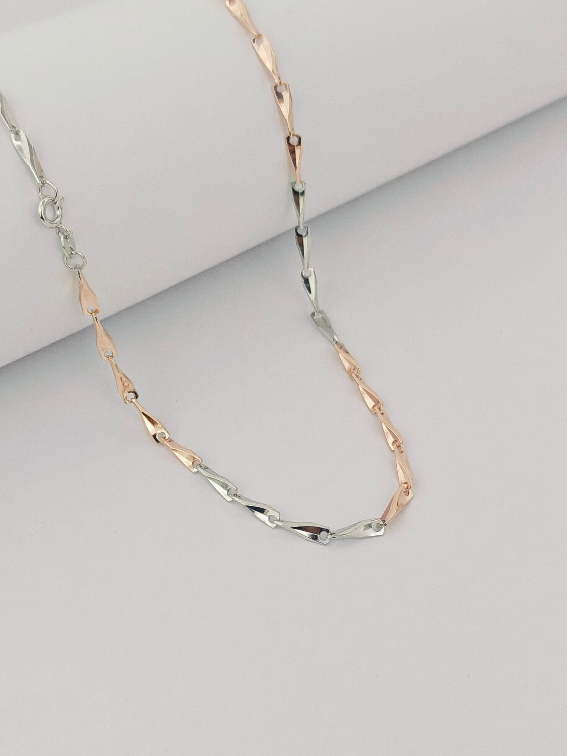Two-tone gold and silver necklace on a light gray background