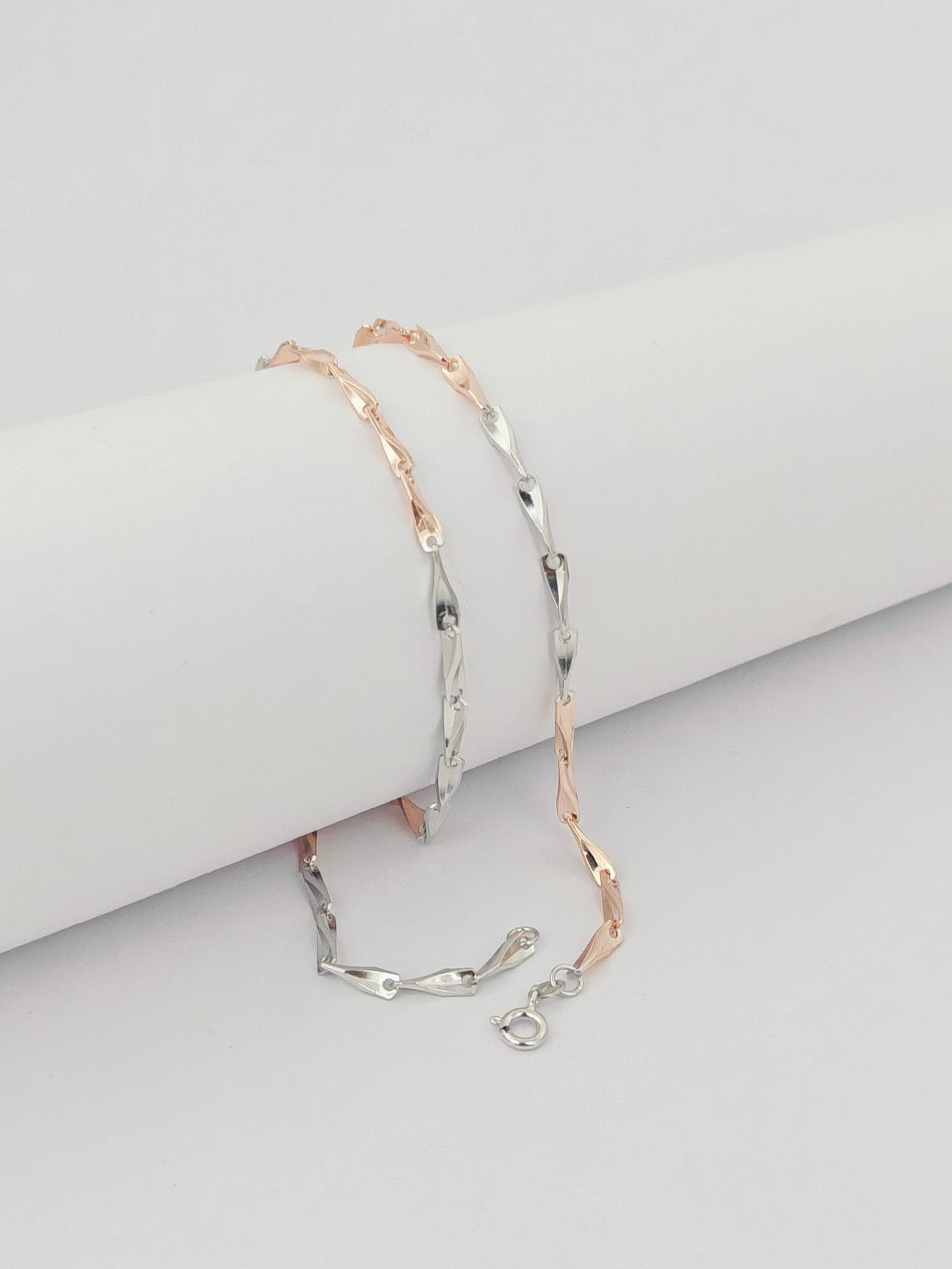 Two silver bracelets with rose gold accents on a light gray surface