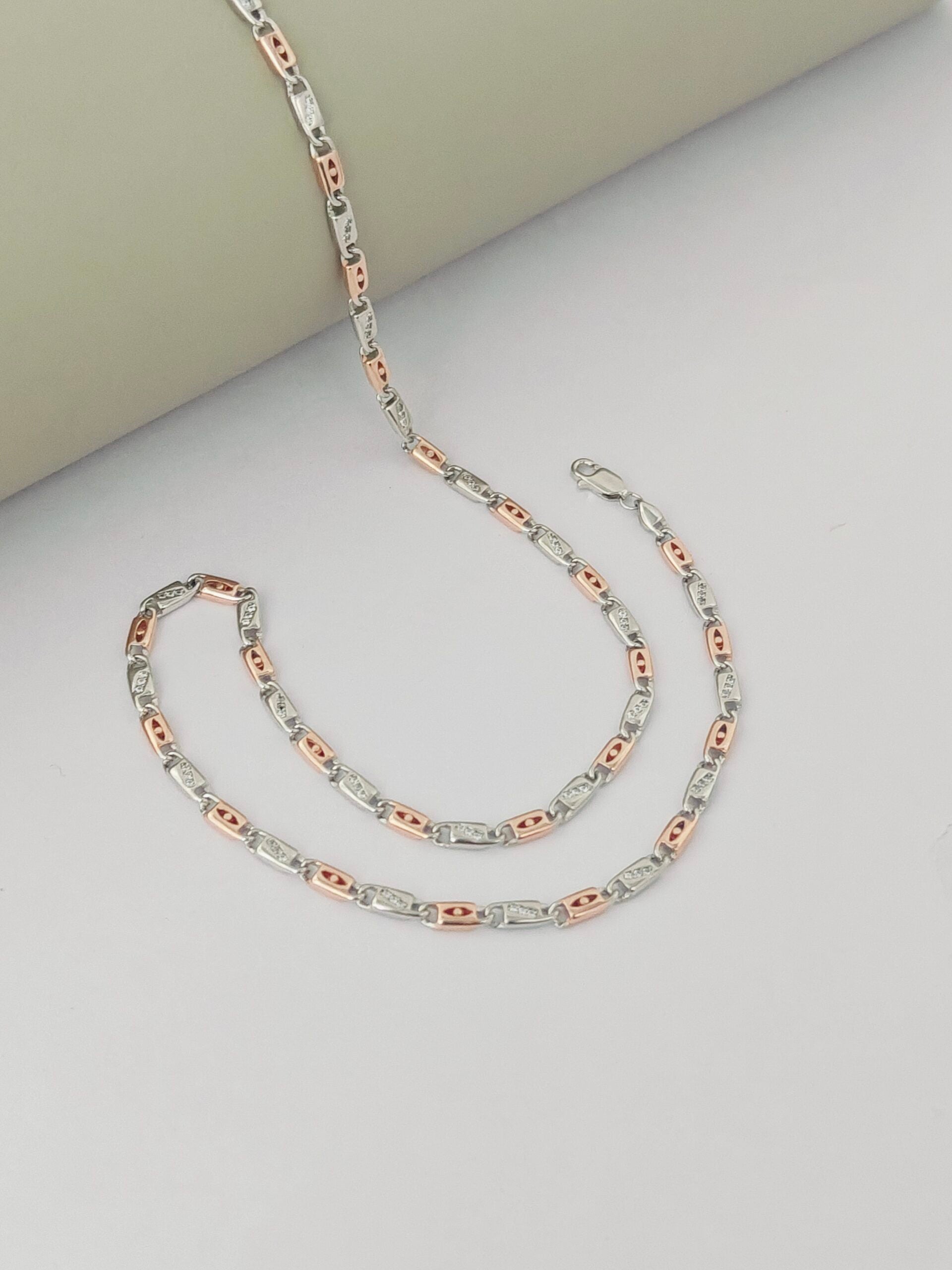 Two rose gold and silver chain necklaces on a light gray surface.