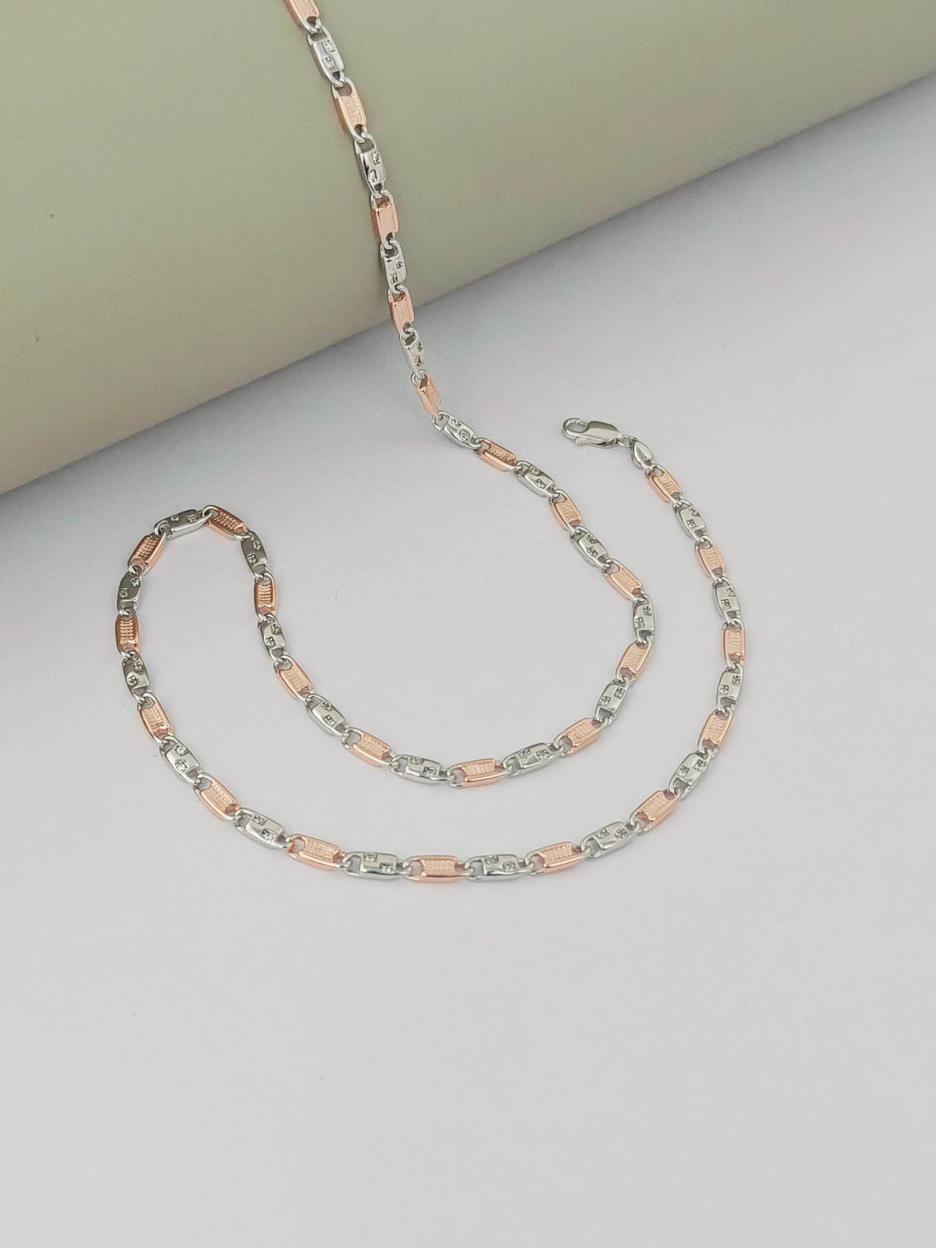 Two necklaces on a light gray surface, one silver and one rose gold.