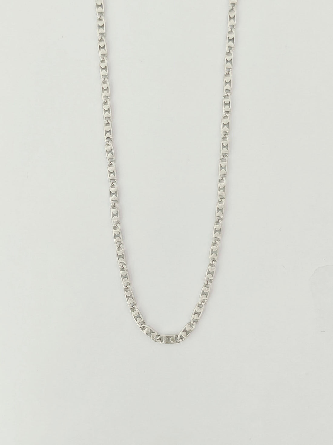 Silver chain necklace on a light gray background