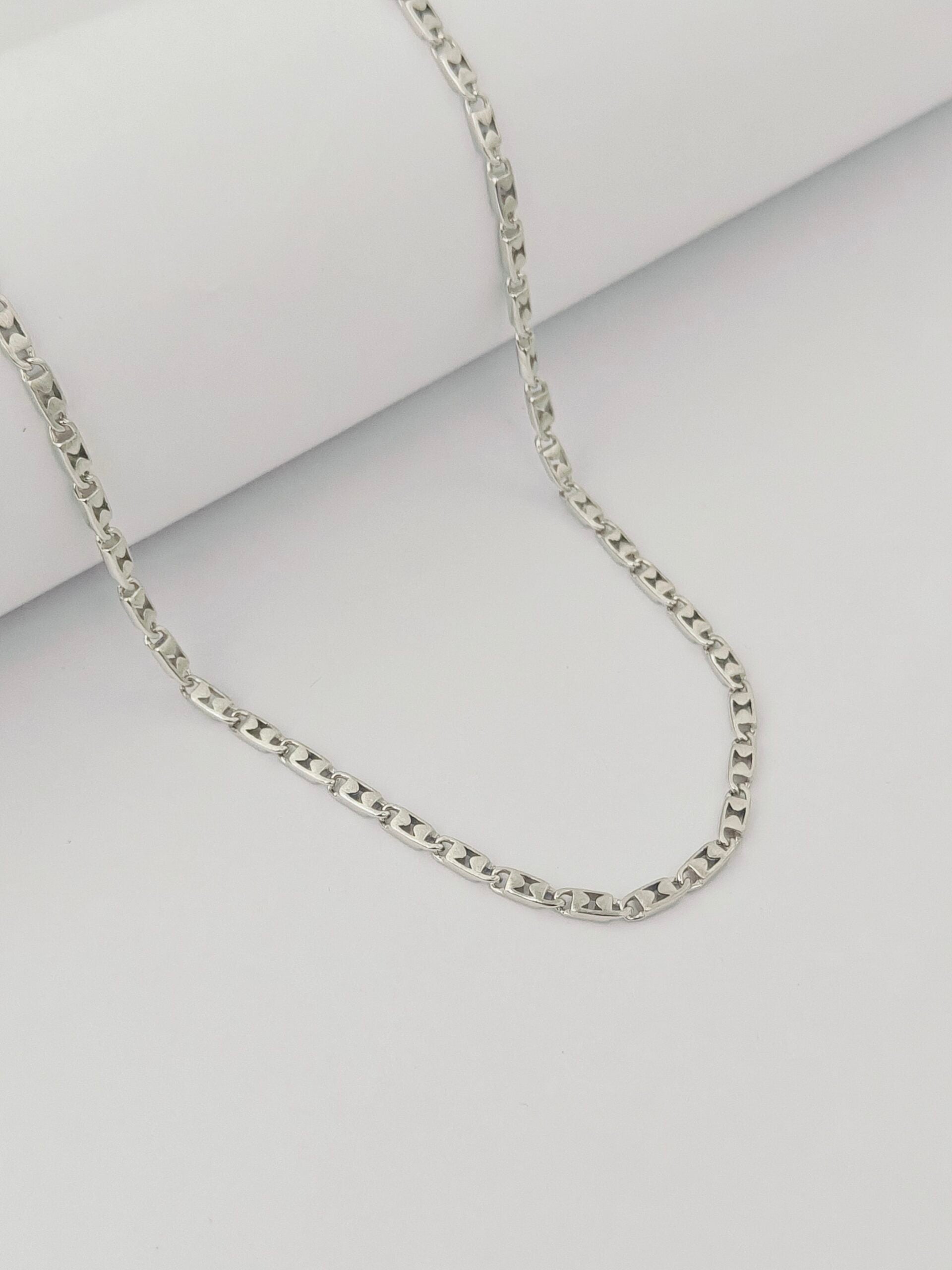 Silver chain necklace on a light gray background