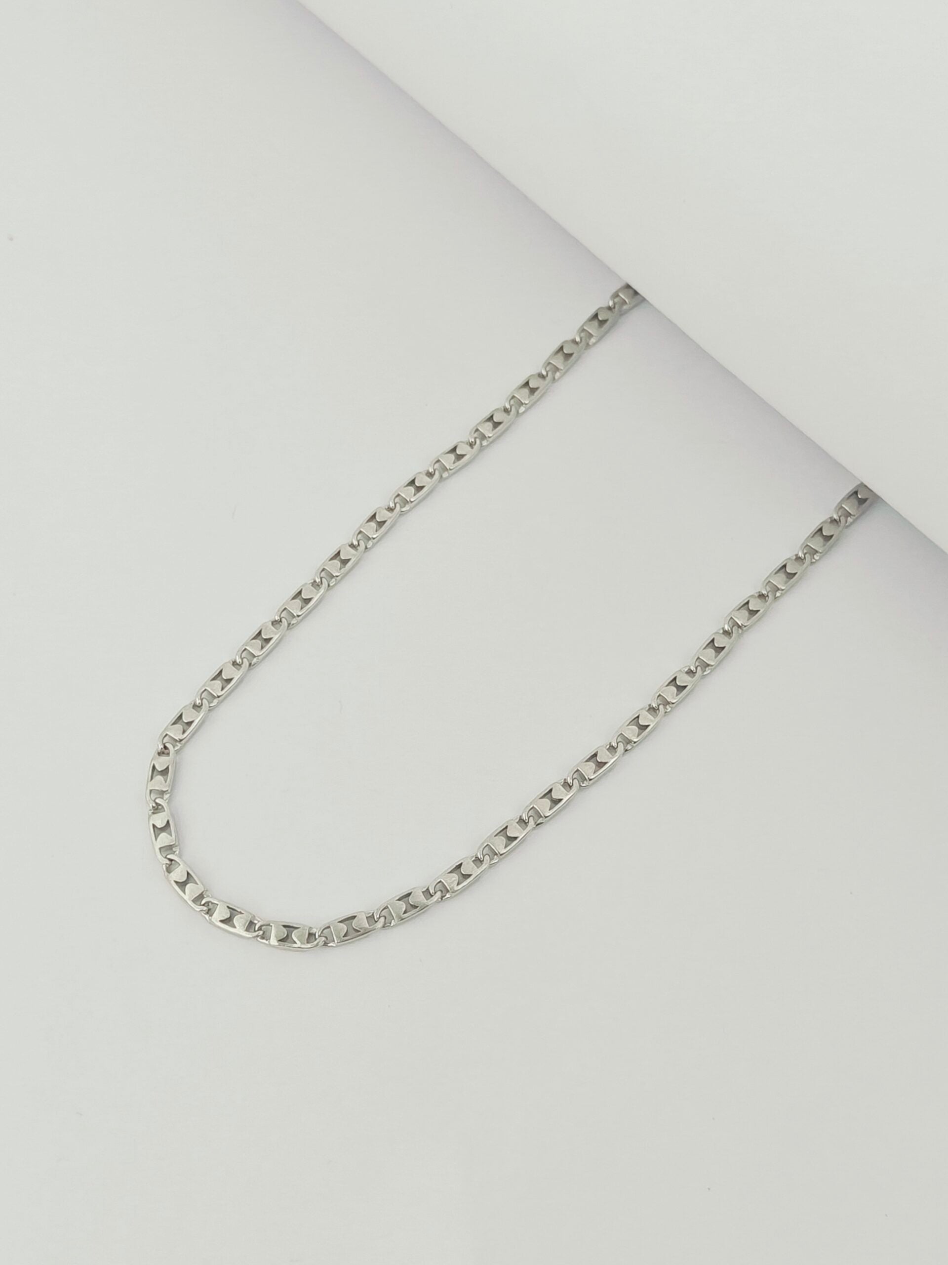Silver chain necklace on a light gray background
