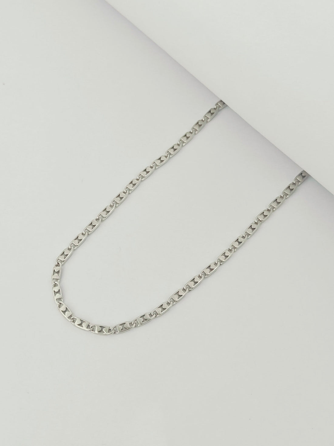 Silver chain necklace on a light gray background