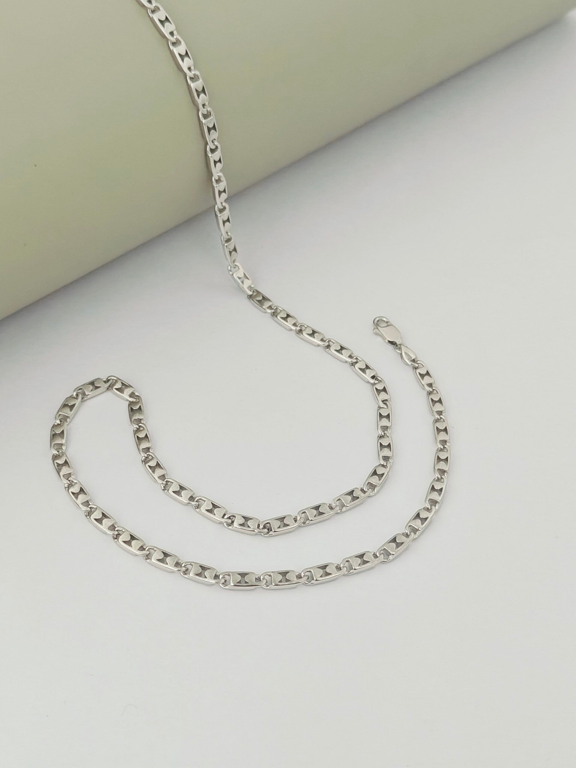 Silver chain necklace on a light gray surface