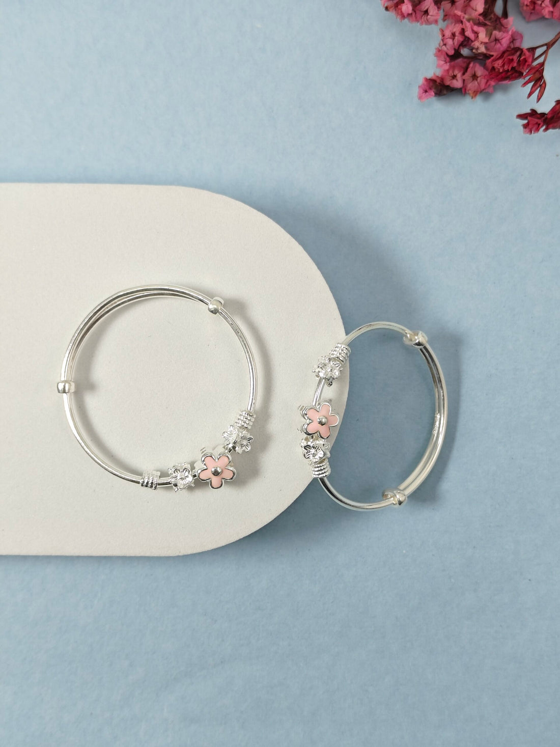 Silver hoop earrings with pink floral accents on a light blue background