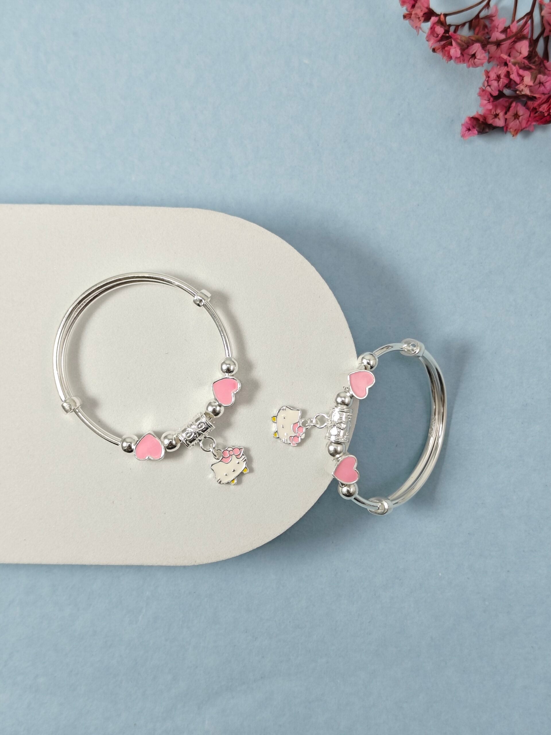 Silver hoop earrings with pink heart and flower charms on a light blue background
