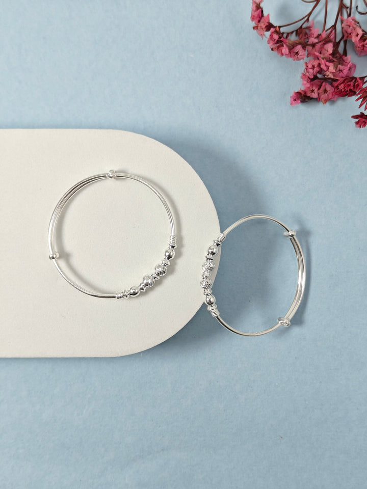 Silver hoop earrings on a light blue background with a white card and pink flowers.