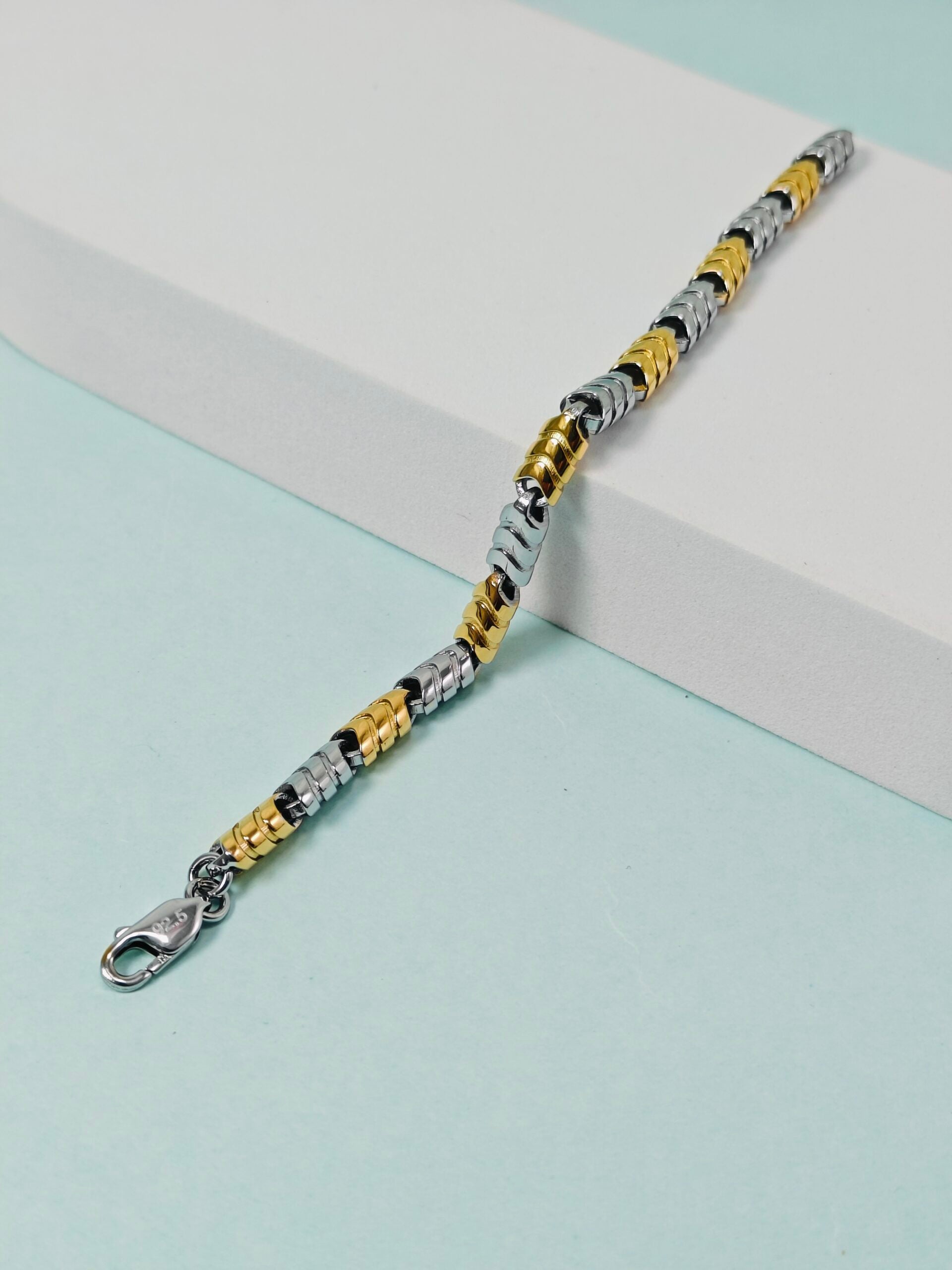 Bracelet with gold, silver, and black links on a light blue background