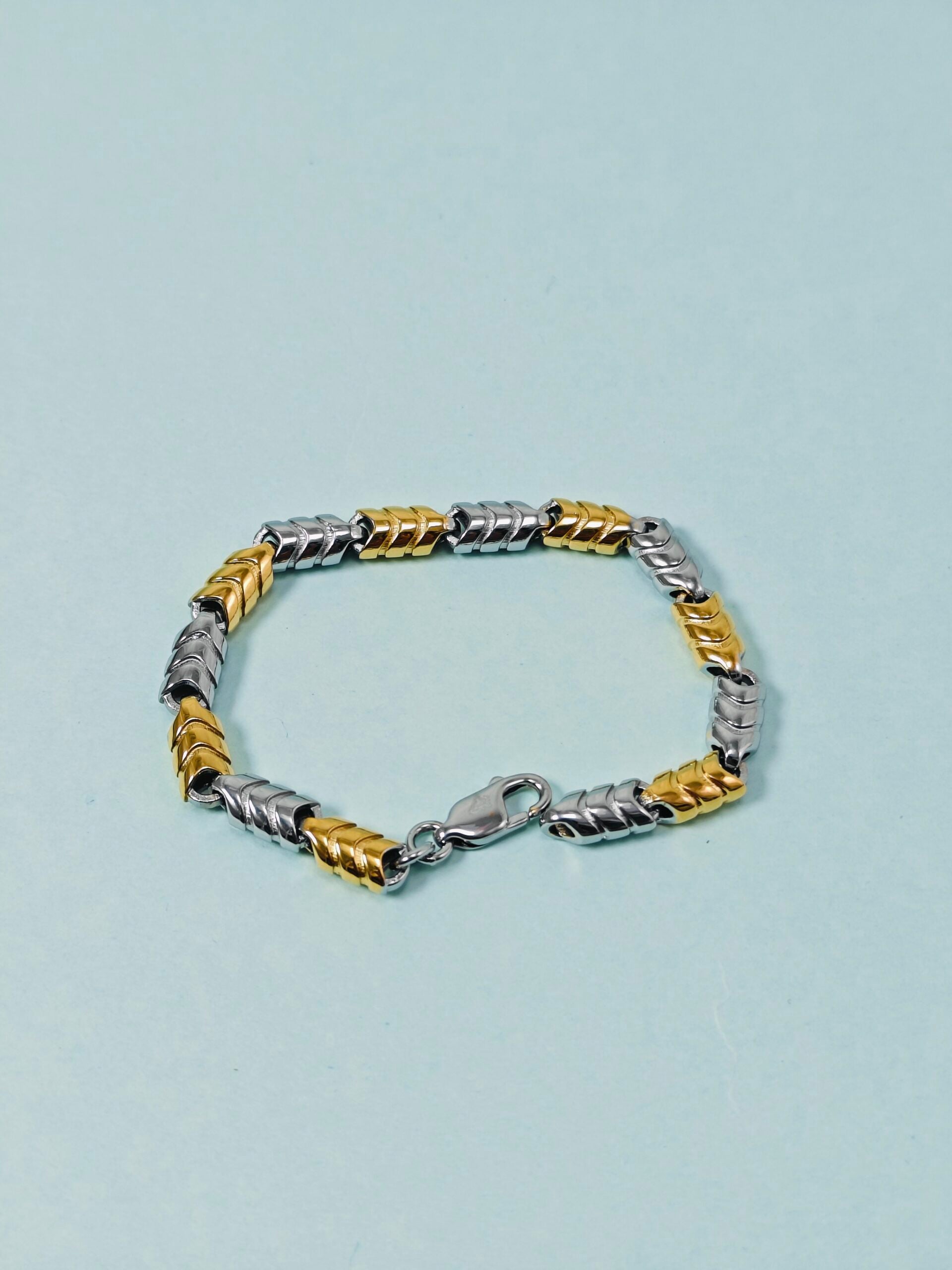 Two-tone silver and gold bracelet on a light blue background
