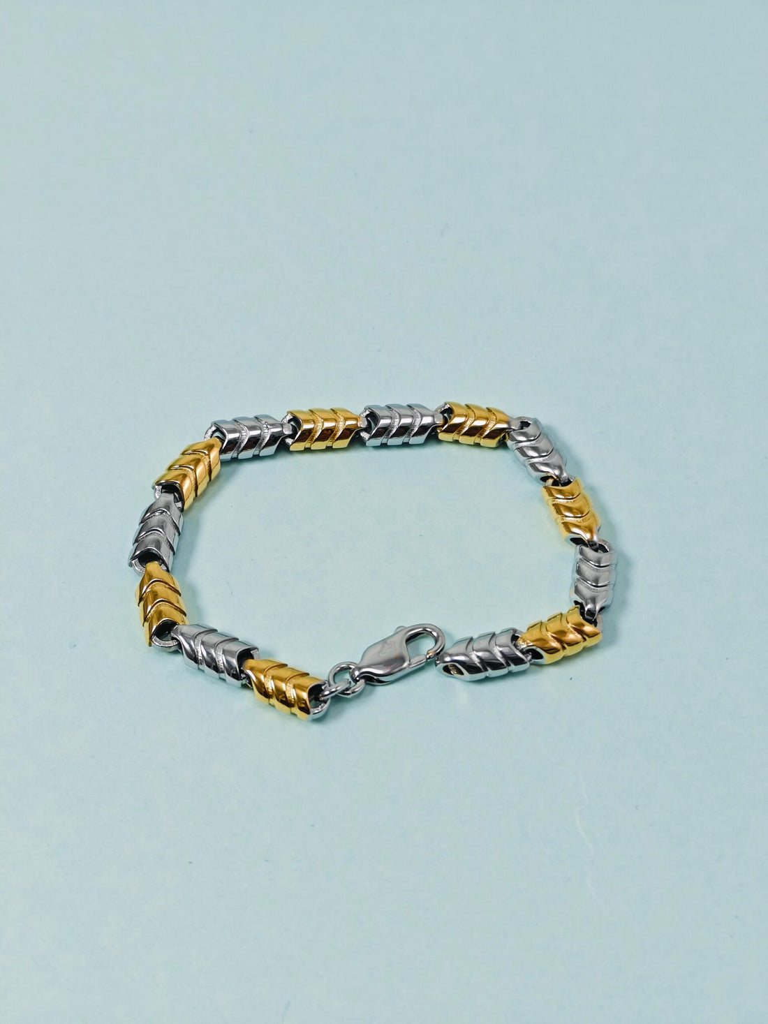 Two-tone silver and gold bracelet on a light blue background