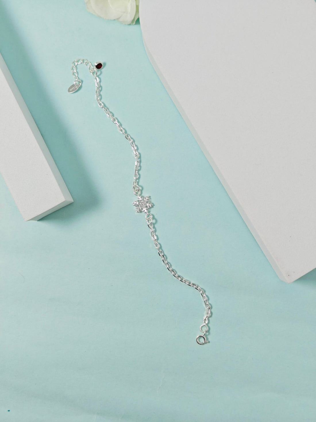 Silver bracelet with a star design on a light blue surface