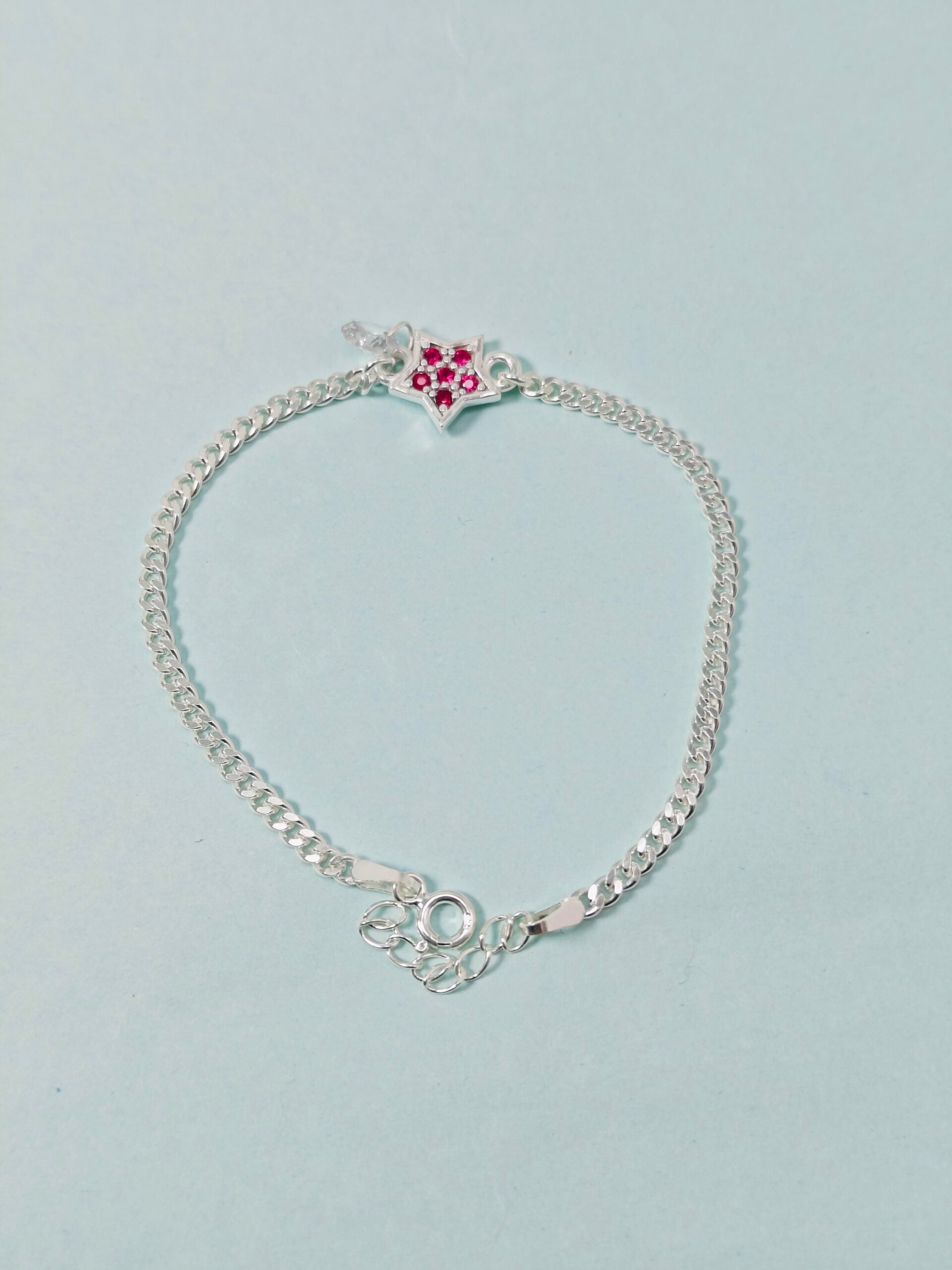 Silver bracelet with a heart-shaped clasp on a light gray background