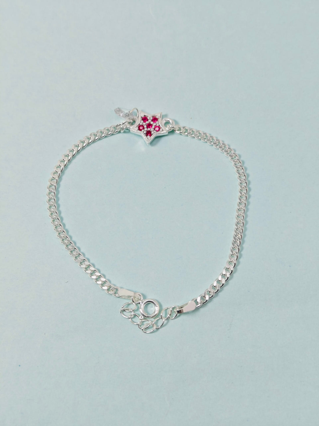 Silver bracelet with a heart-shaped clasp on a light gray background