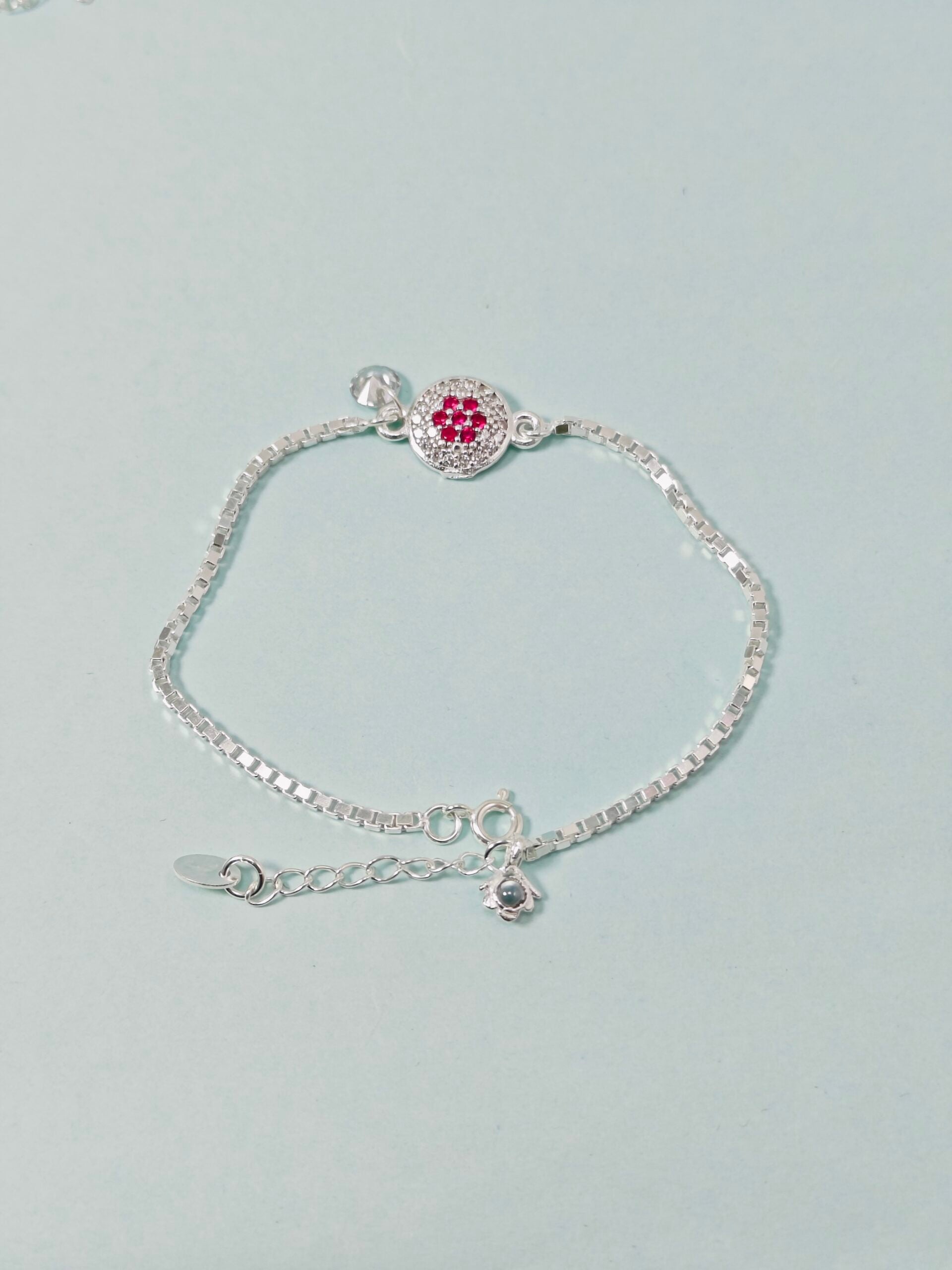 Silver bracelet with a heart-shaped charm on a light gray background