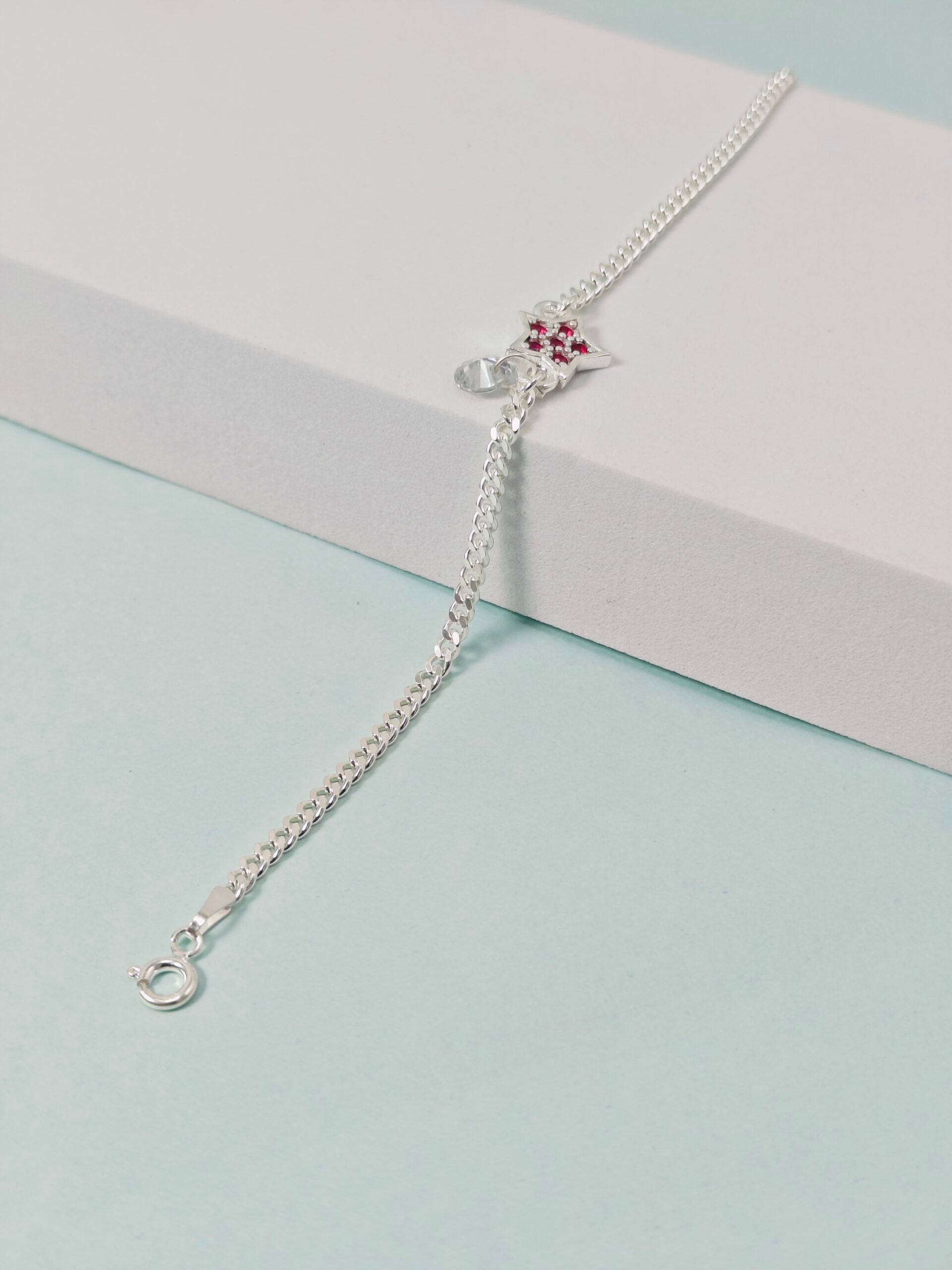 Silver bracelet with a star-shaped clasp on a light blue and pink background