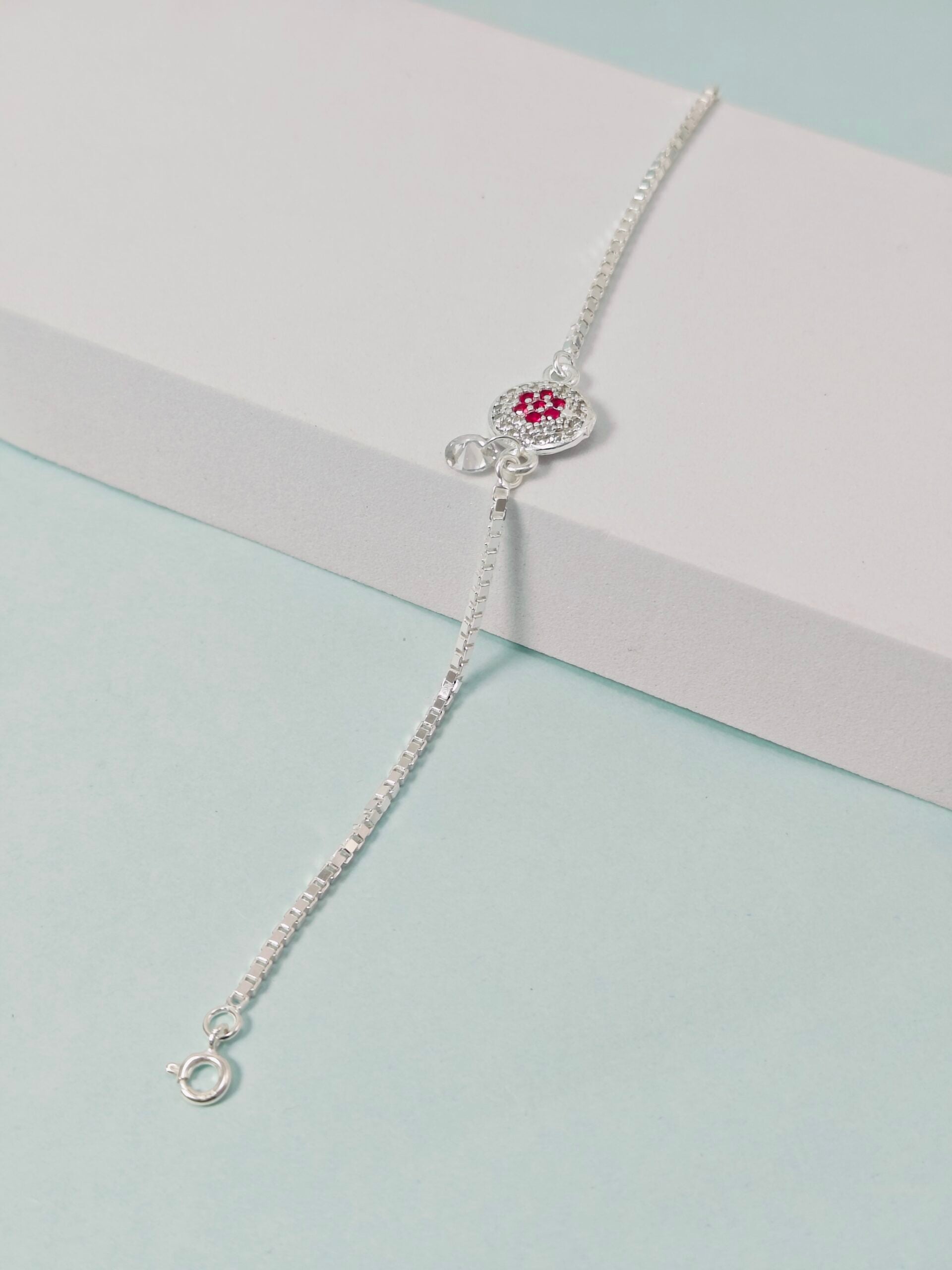 Silver bracelet with a heart-shaped clasp on a light blue background