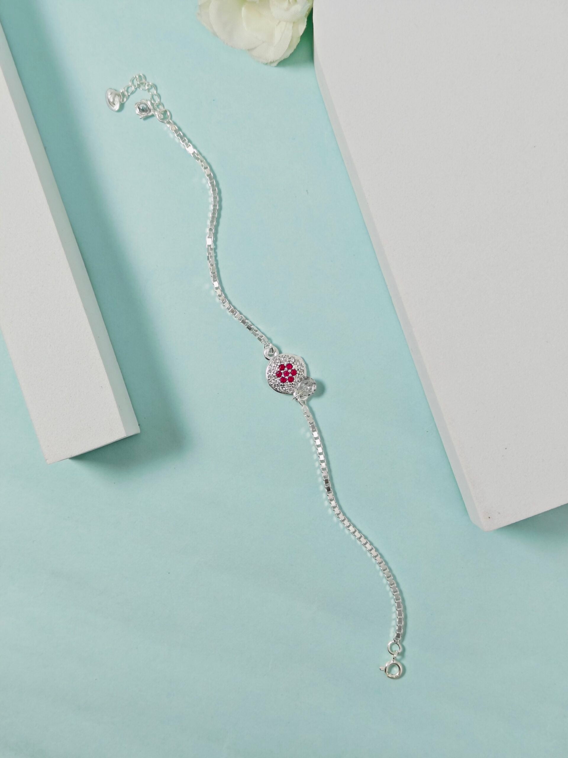Silver bracelet with a red gemstone on a light blue surface