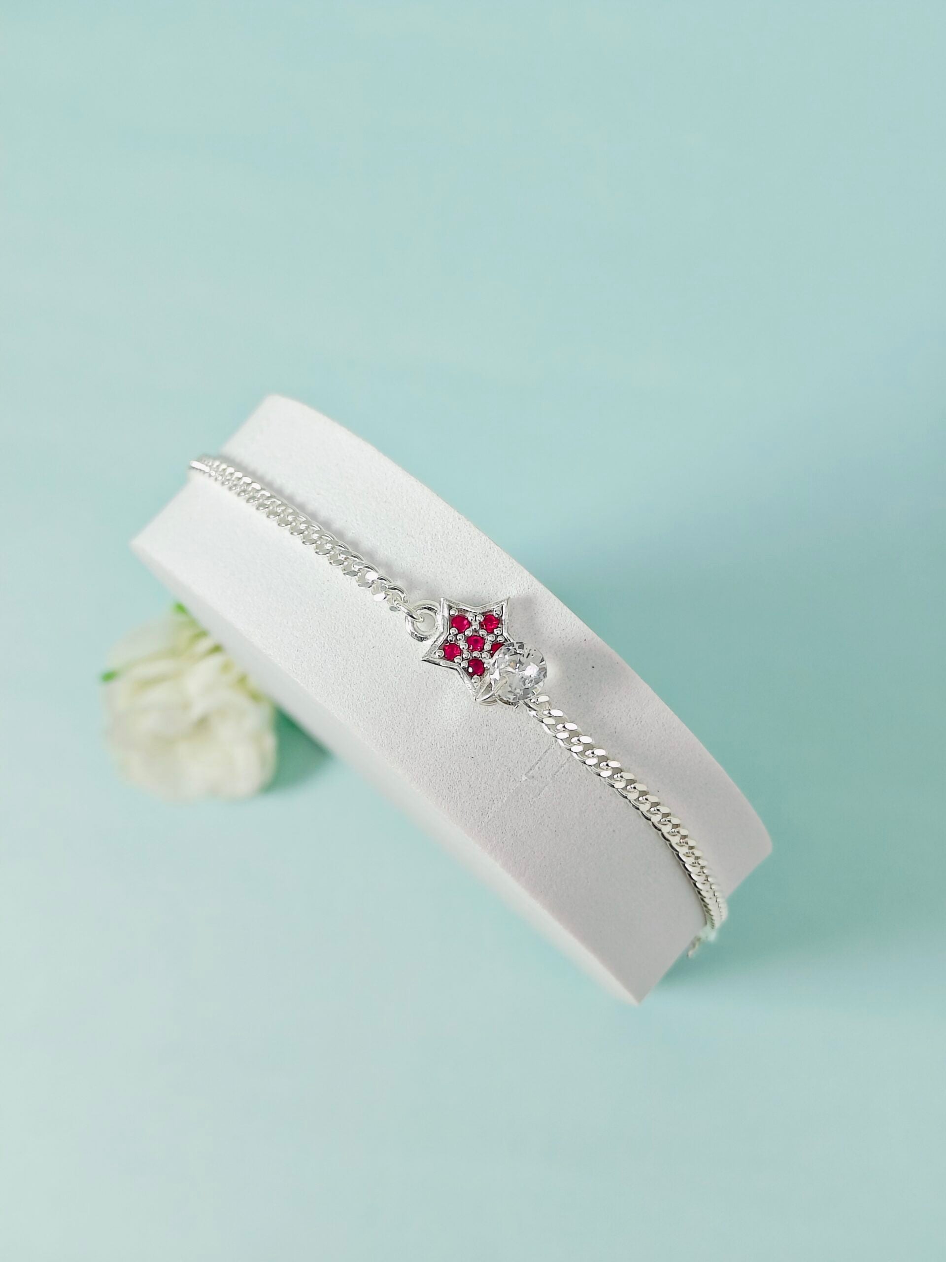 Silver bracelet with a floral clasp on a white box against a light blue background