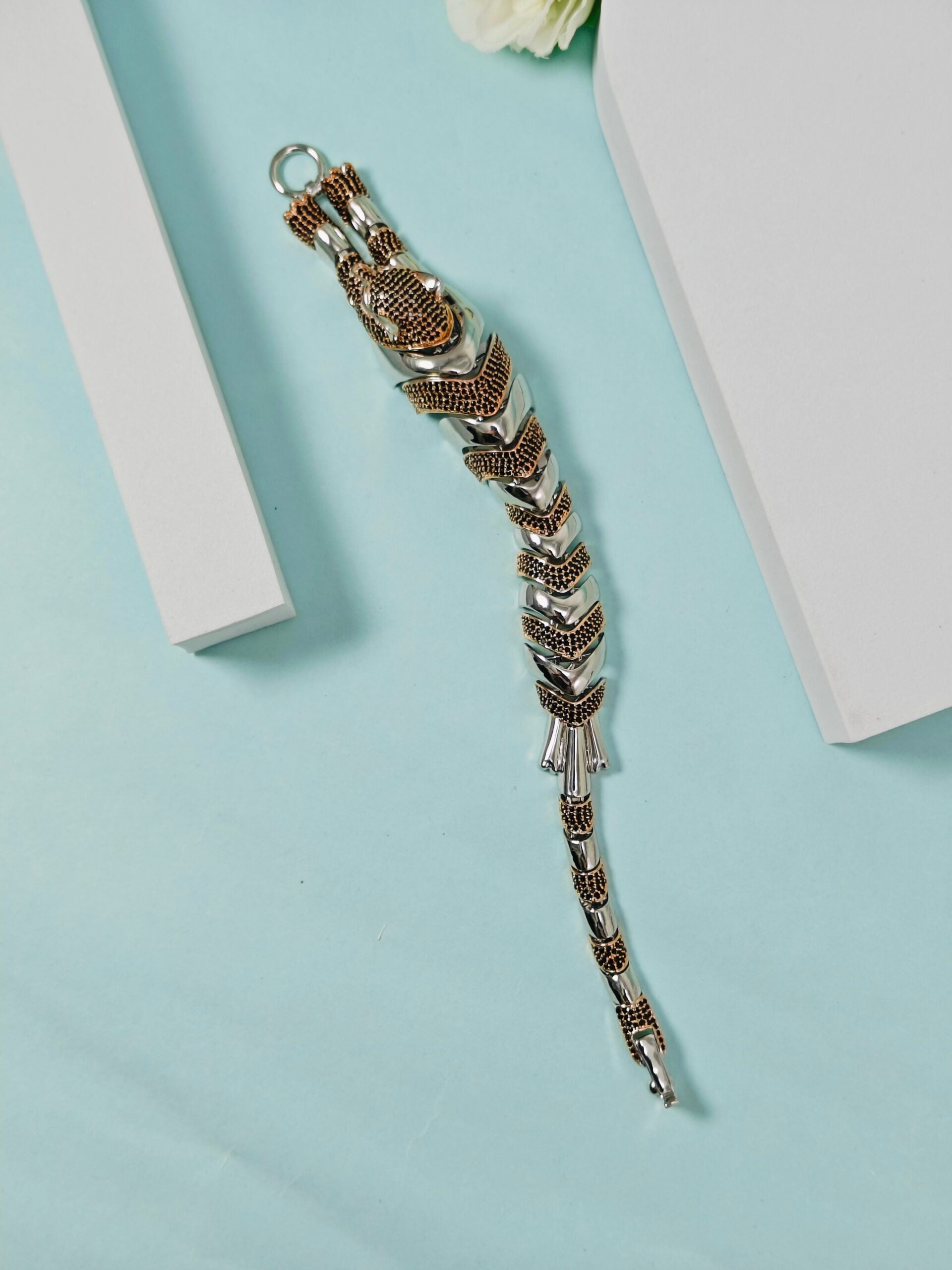 Silver bracelet with intricate design on a light blue background