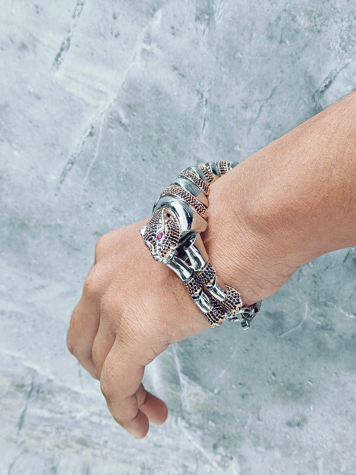Hand wearing multiple silver bracelets on a marble background