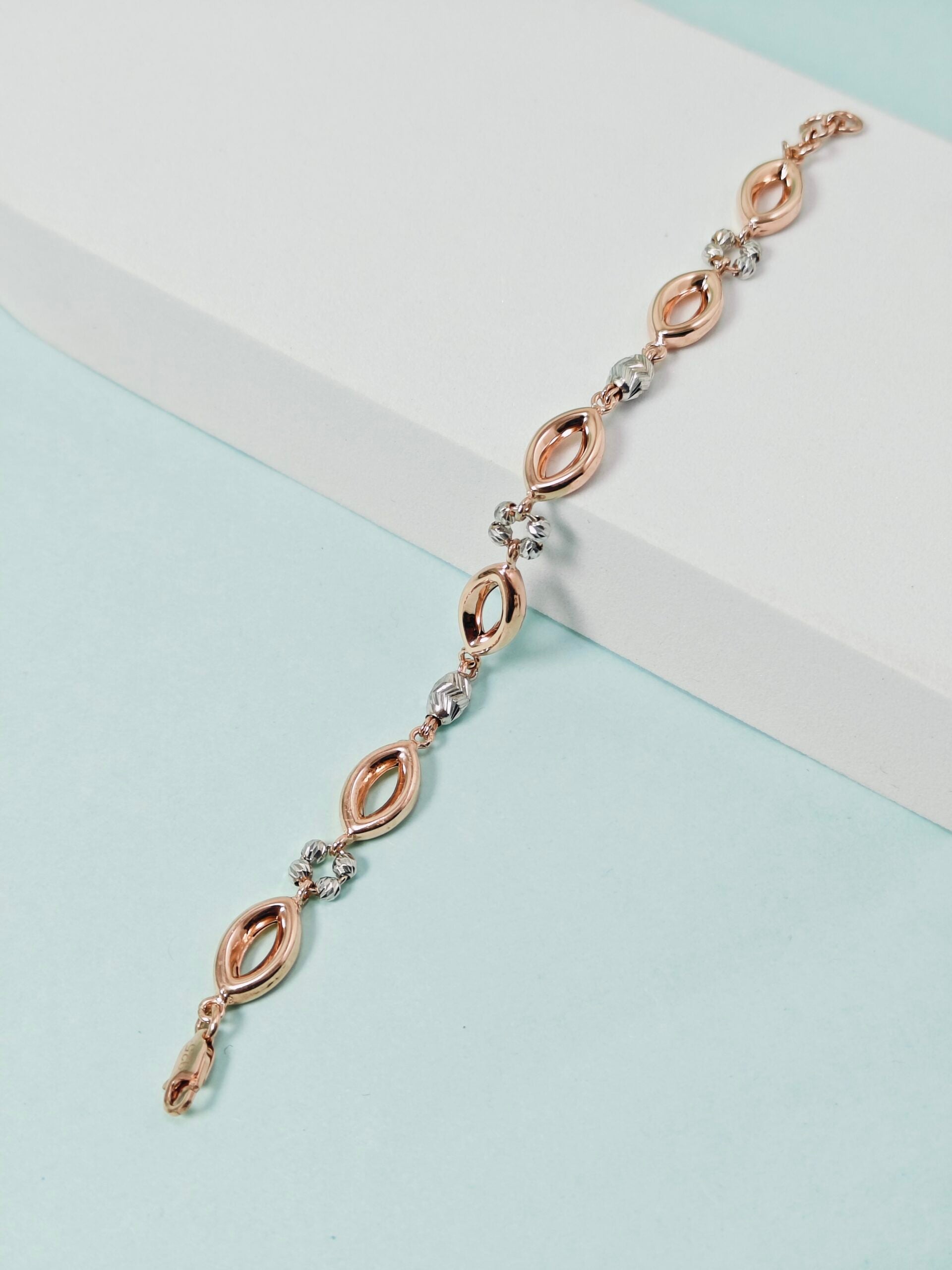 Rose gold and silver bracelet on a light blue background