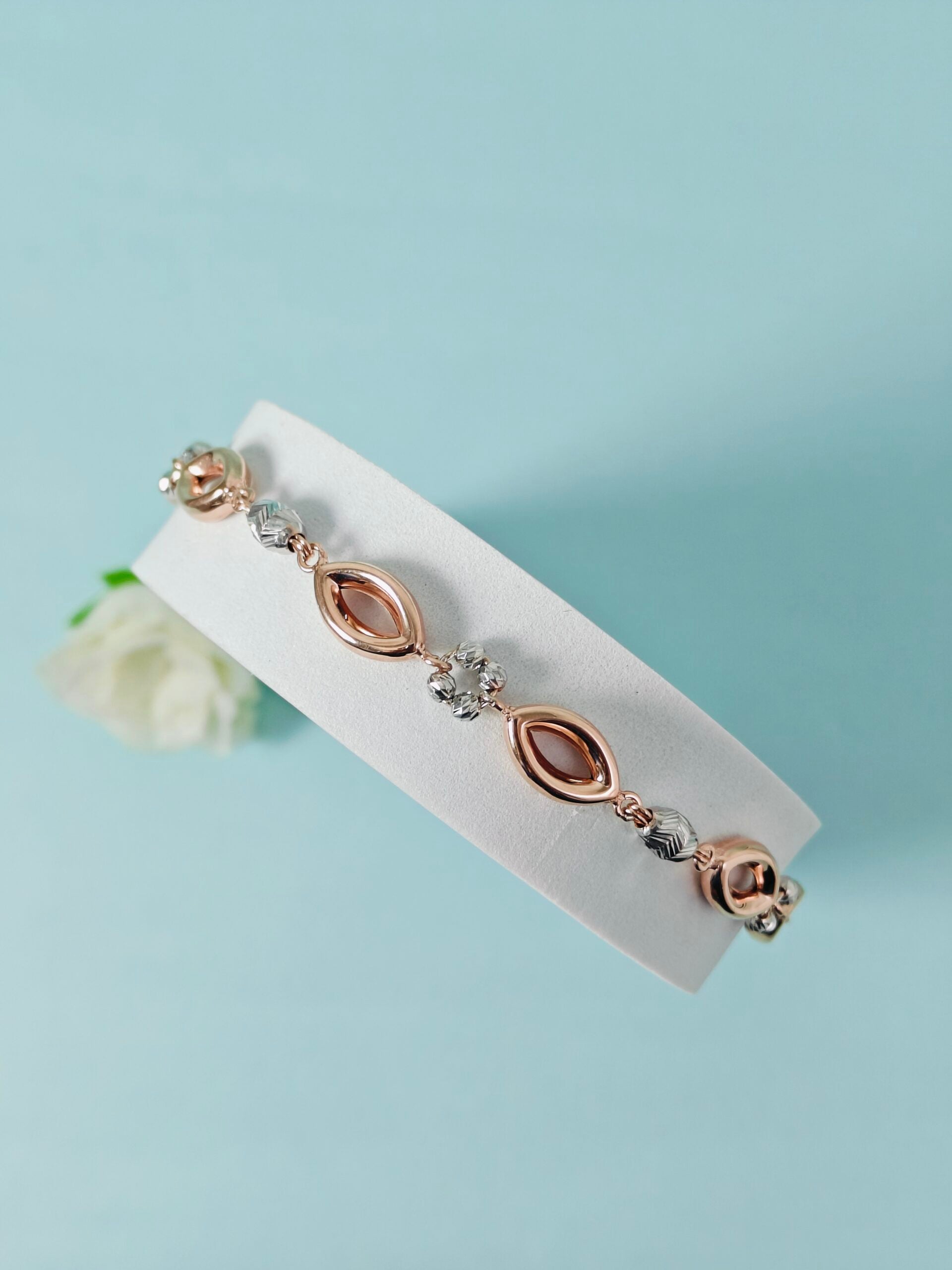 Rose gold bracelet with gemstones on a light blue background