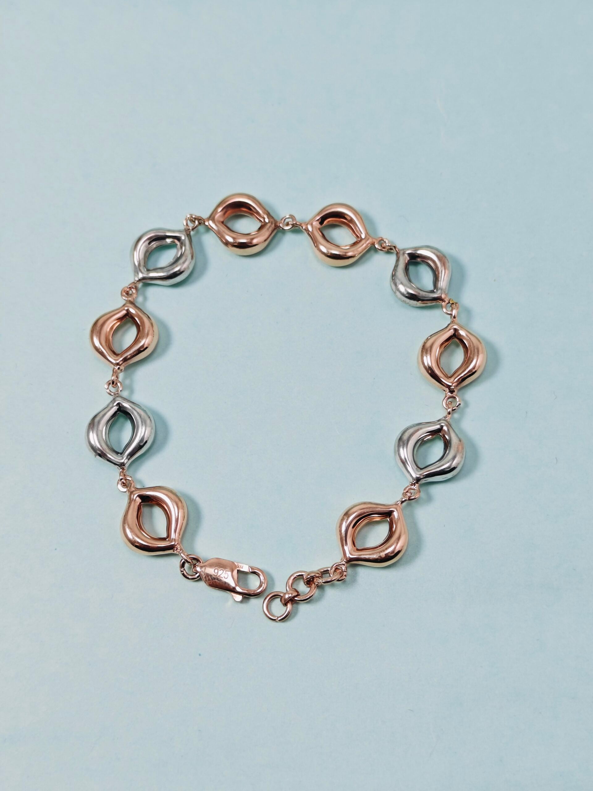 Rose gold and silver bracelet on a light blue background