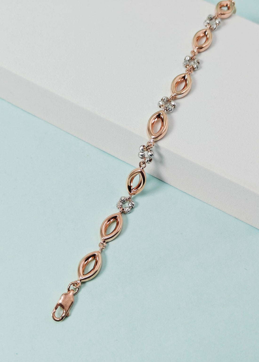 Rose gold bracelet with clear stones on a light blue and white background