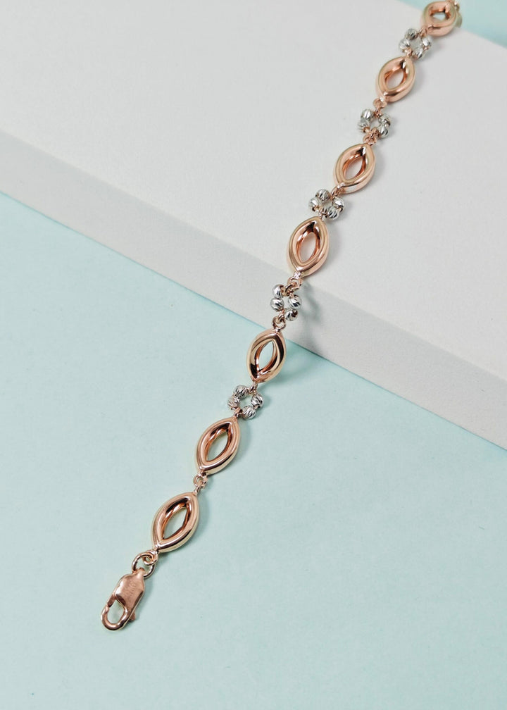 Rose gold bracelet with clear stones on a light blue and white background