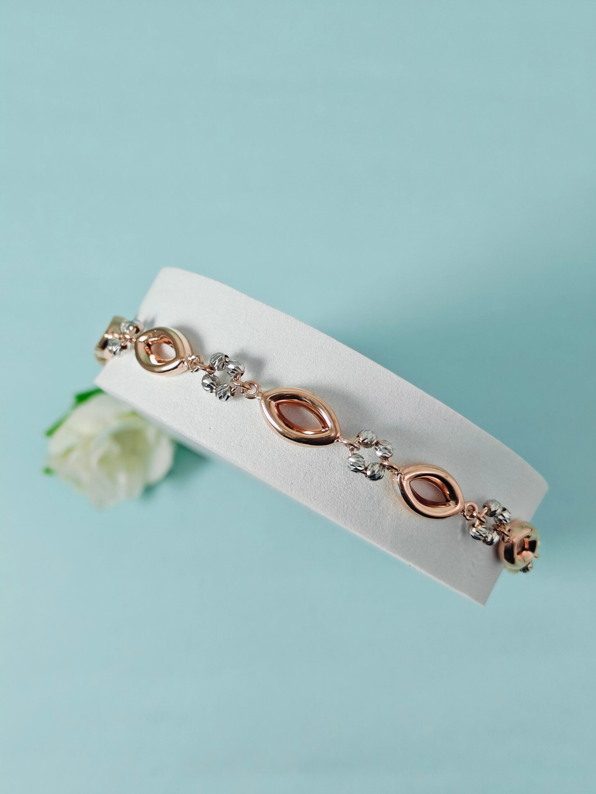 Rose gold bracelet with diamonds on a white card against a light blue background