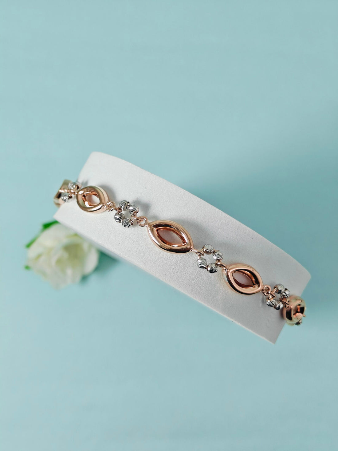 Rose gold bracelet with diamonds on a white card against a light blue background