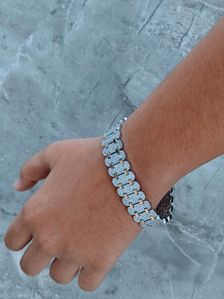 Silver chain bracelet on a wrist against a gray concrete background