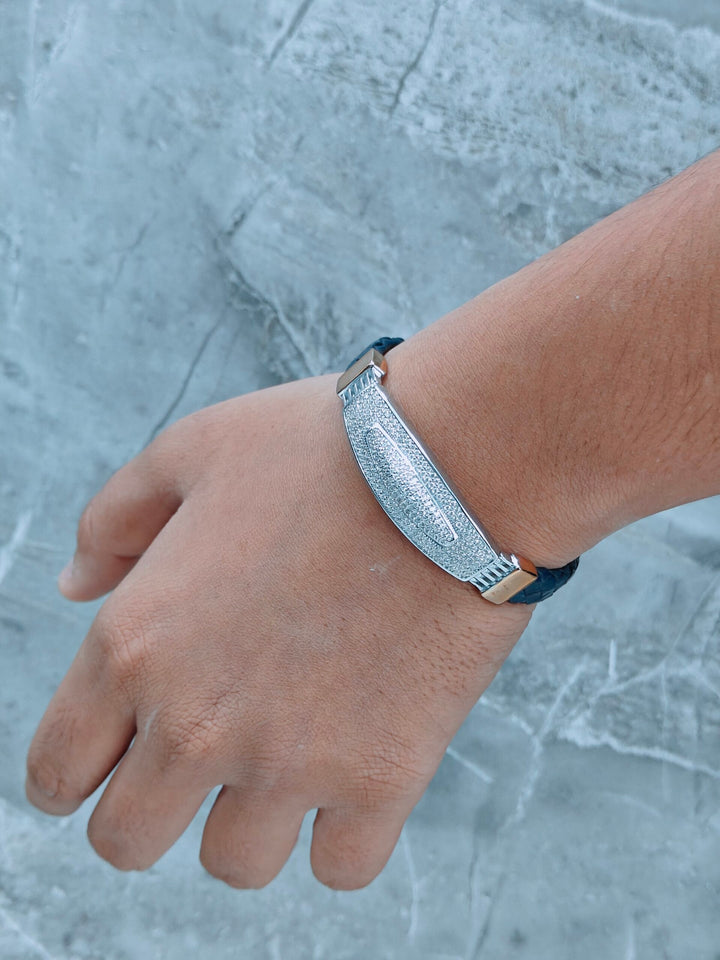 Hand wearing a silver bracelet on a textured gray background