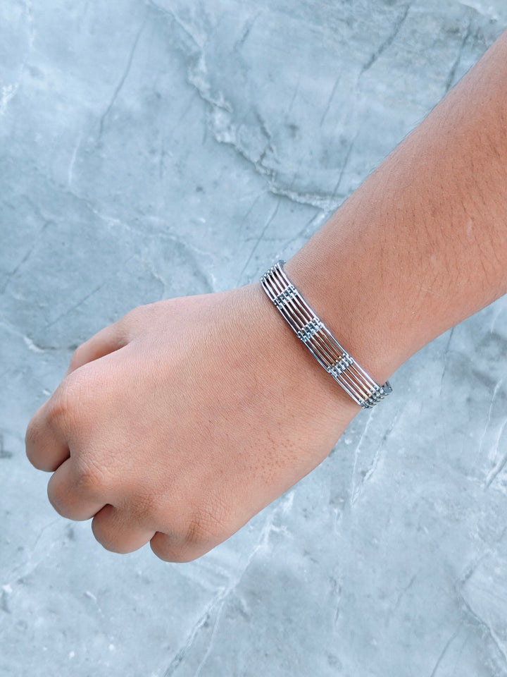 Silver bracelet on a wrist against a light gray marble background