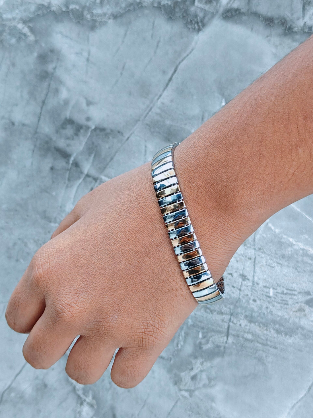 Silver bracelet on a wrist against a gray marble background