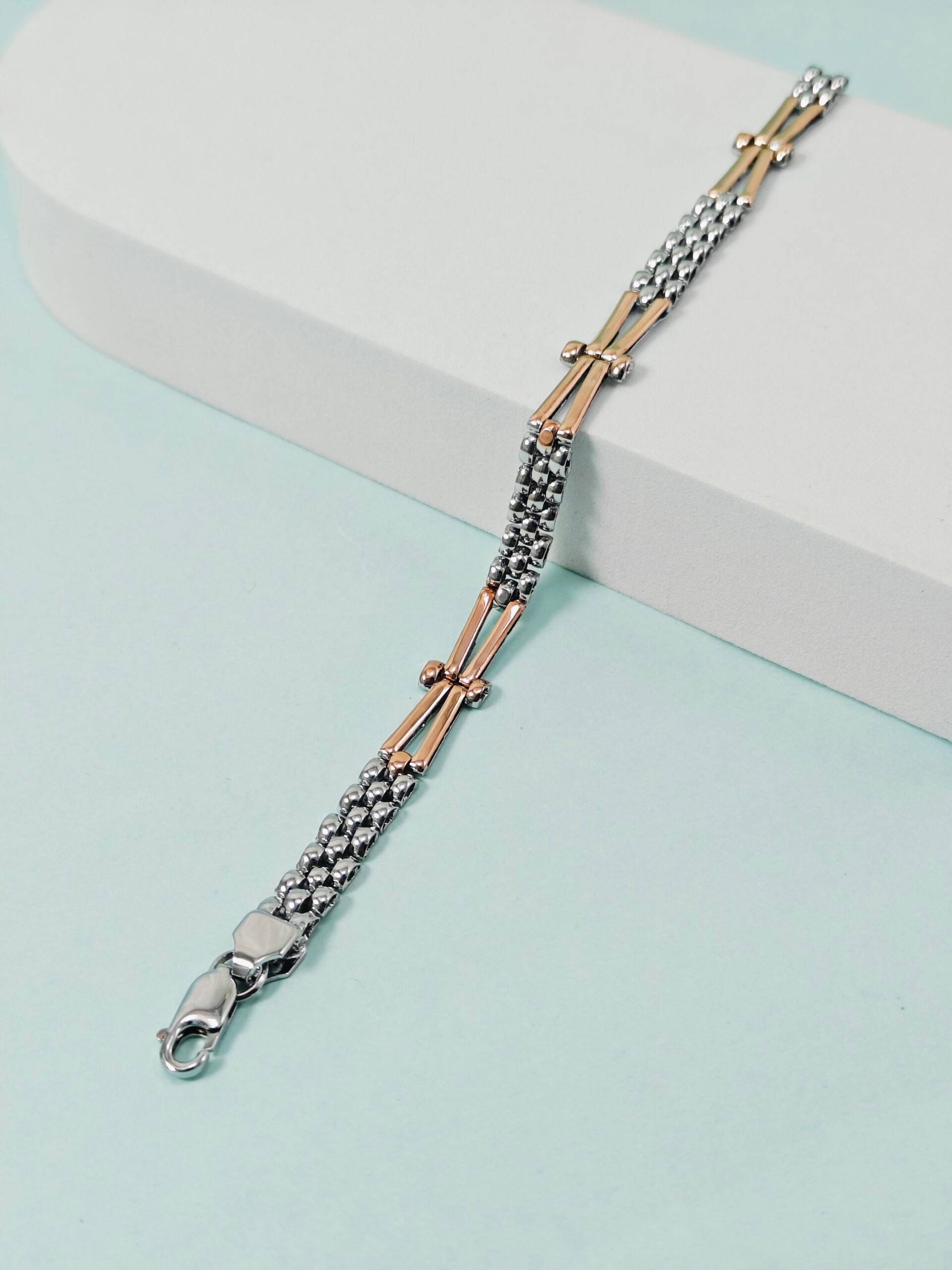 Two-tone bracelet with silver and rose gold accents on a light blue background