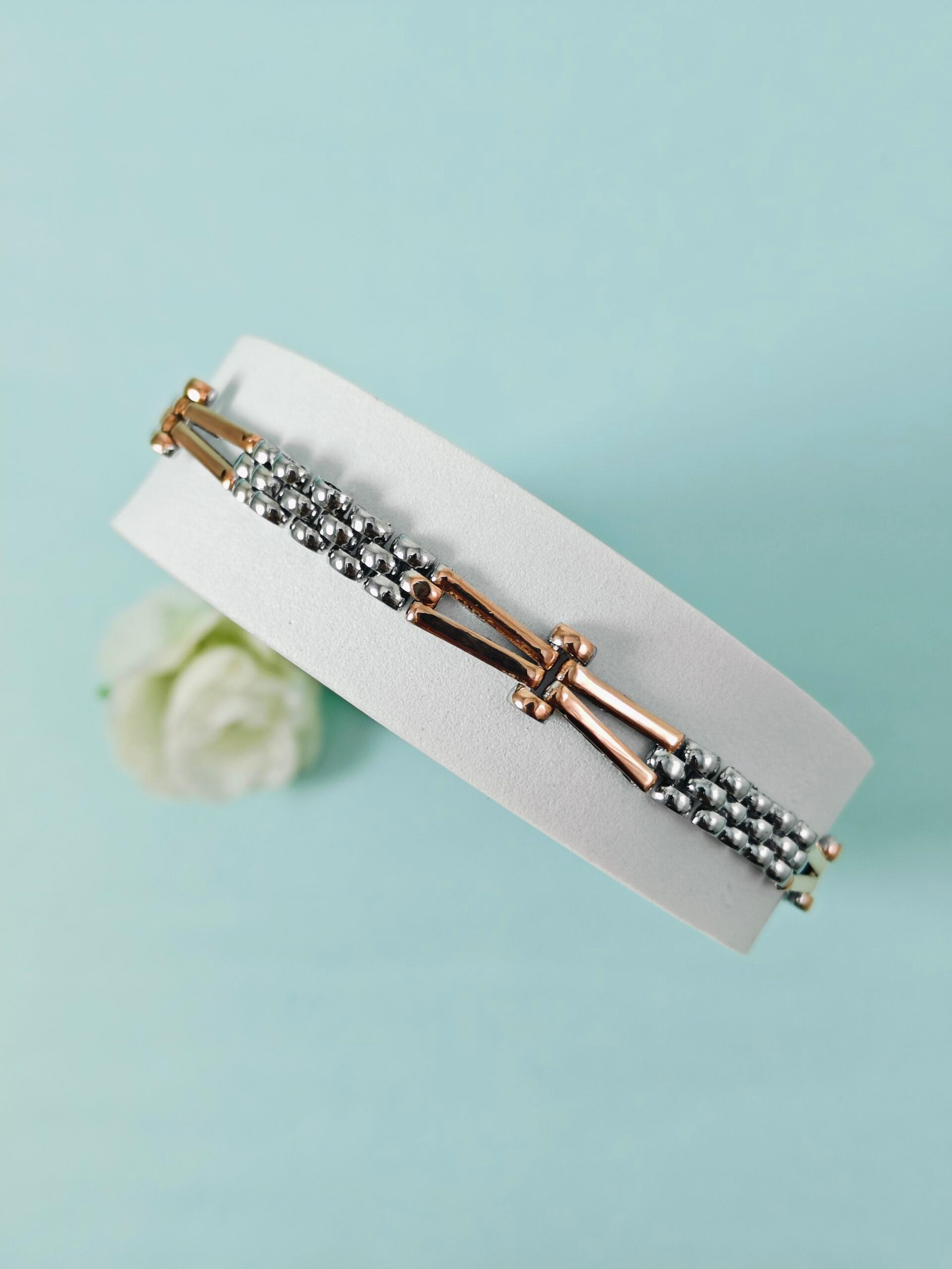 Bracelet with gold and silver beads on a light blue background