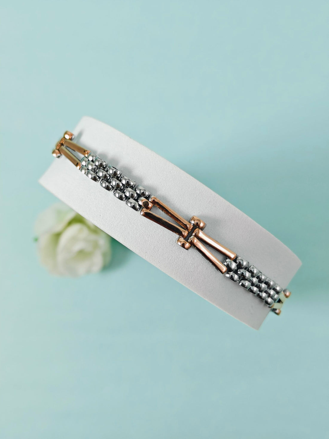 Bracelet with gold and silver beads on a light blue background