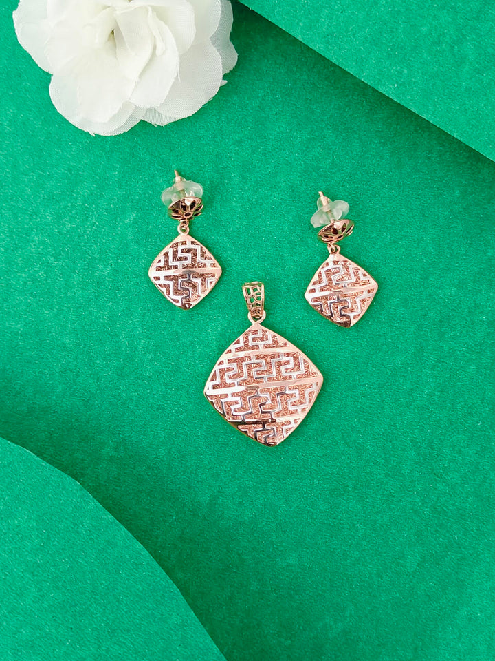 Rose gold jewelry set with pendant and earrings on a green background