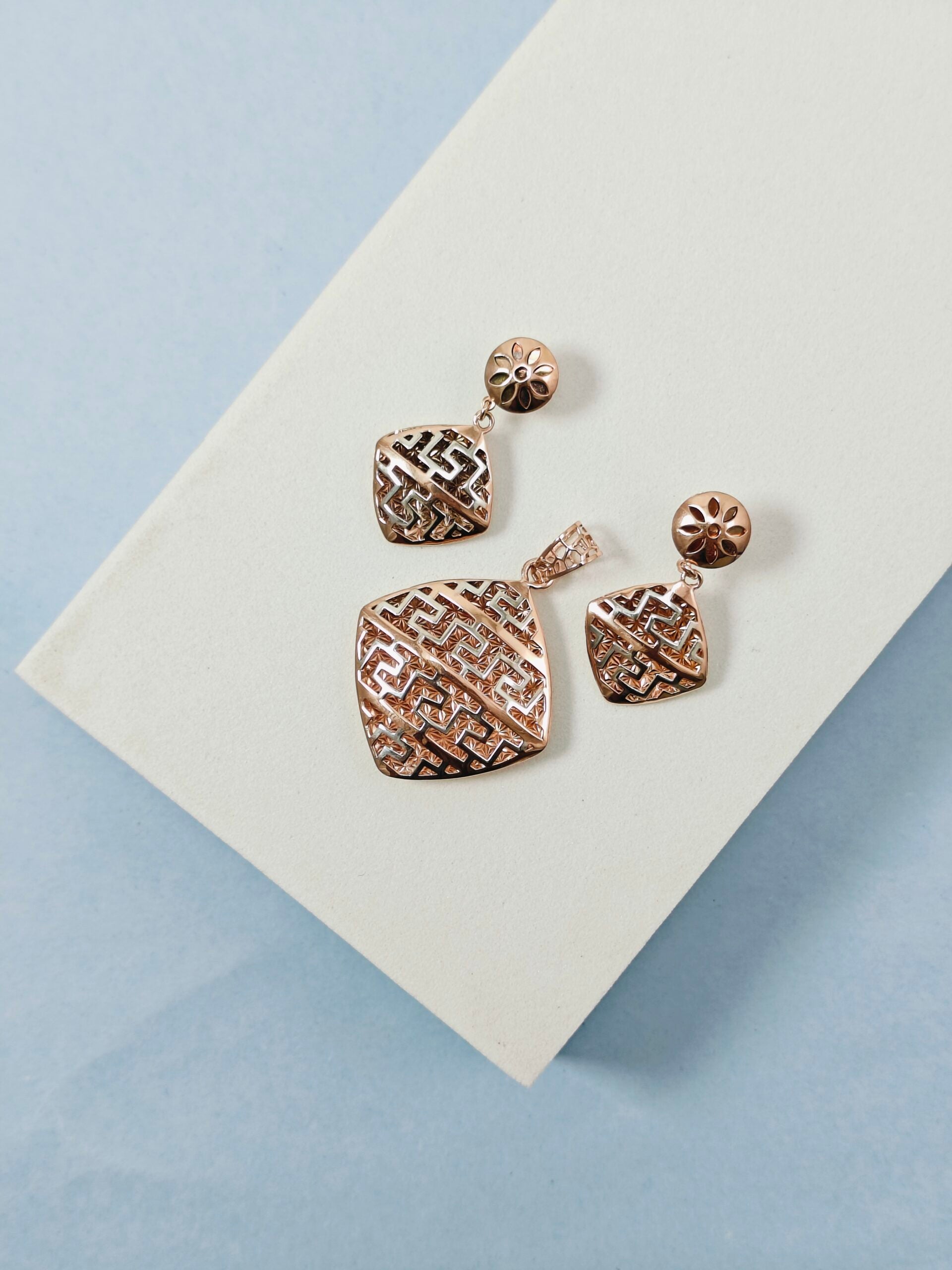Pair of rose gold earrings on a light blue background