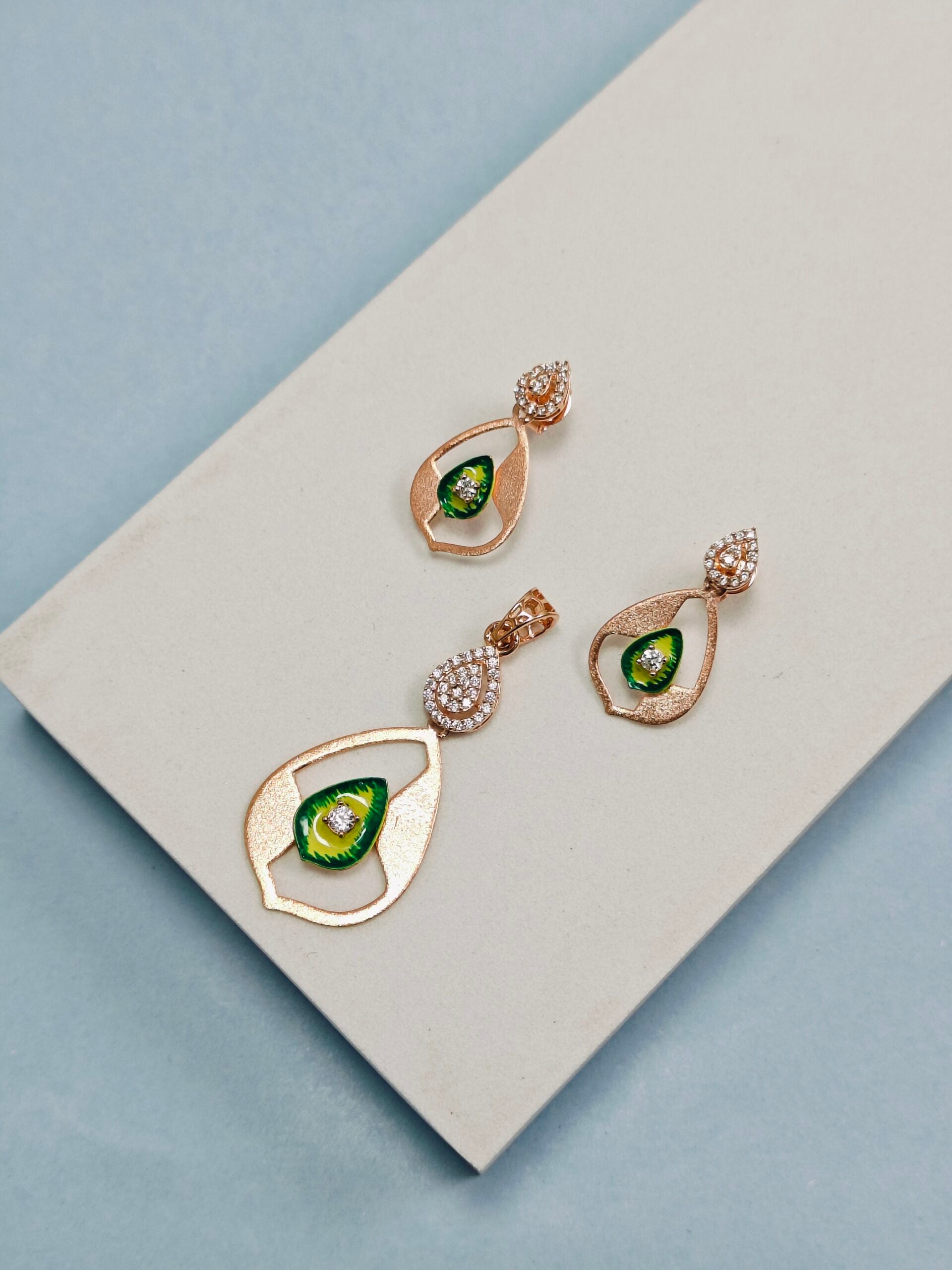 Gold earrings with green gemstones on a light gray surface