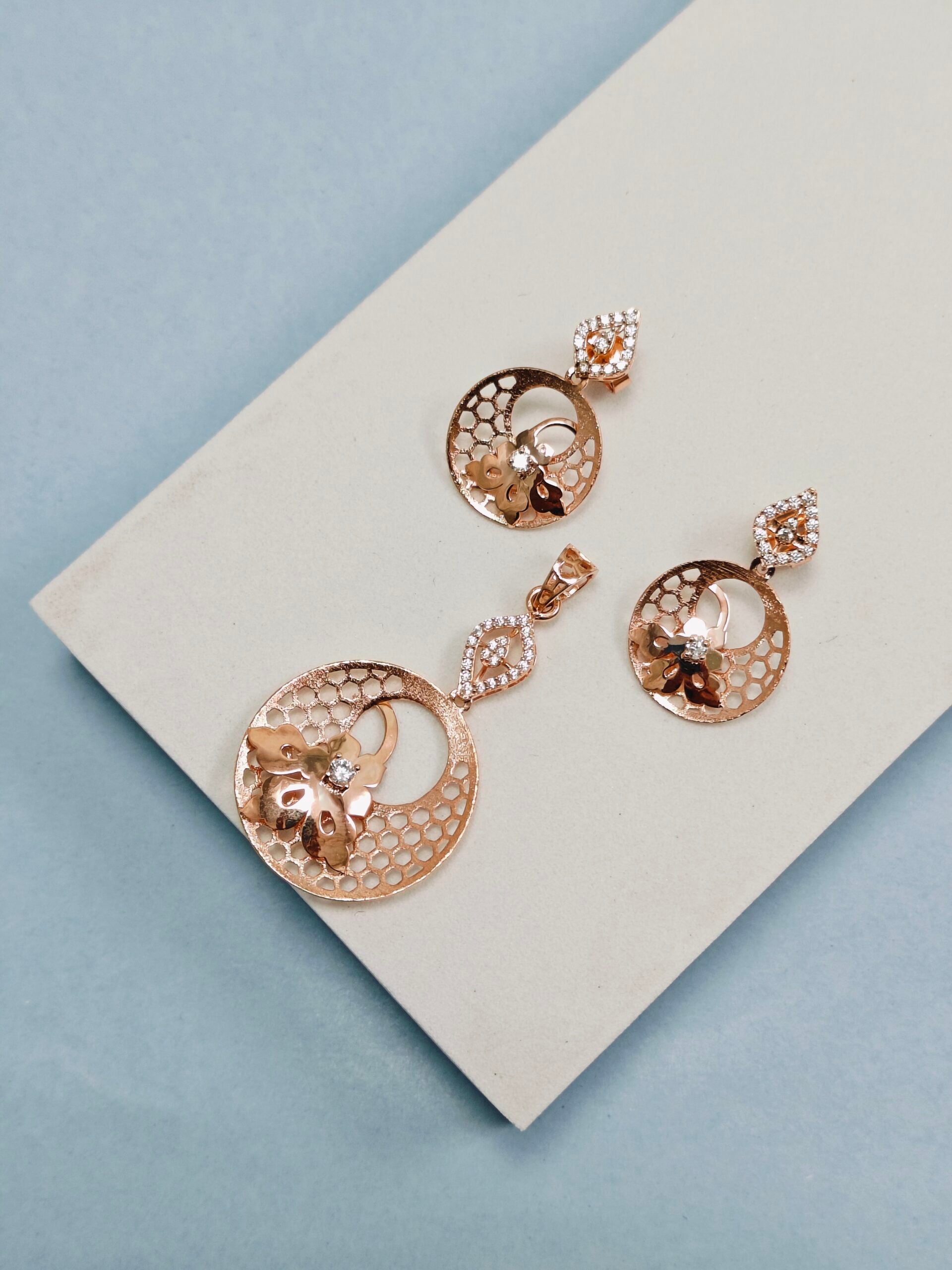 Rose gold earrings on a white card with a light blue background
