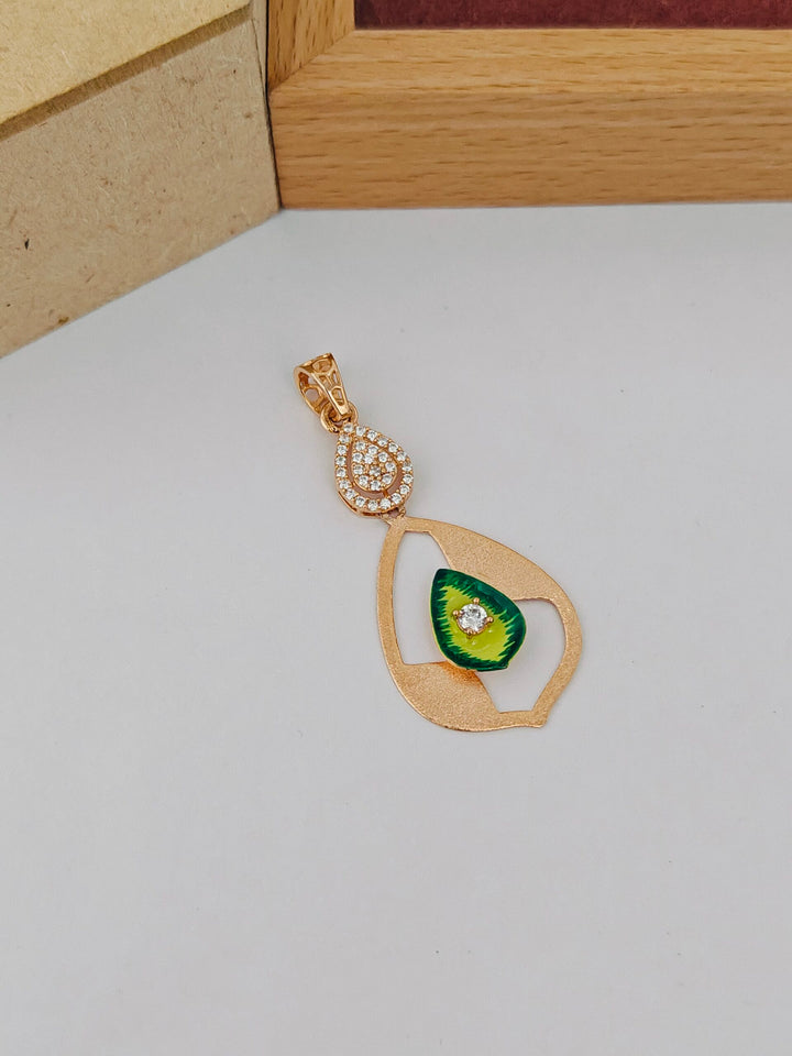 Gold pendant with green gemstone on a light gray surface