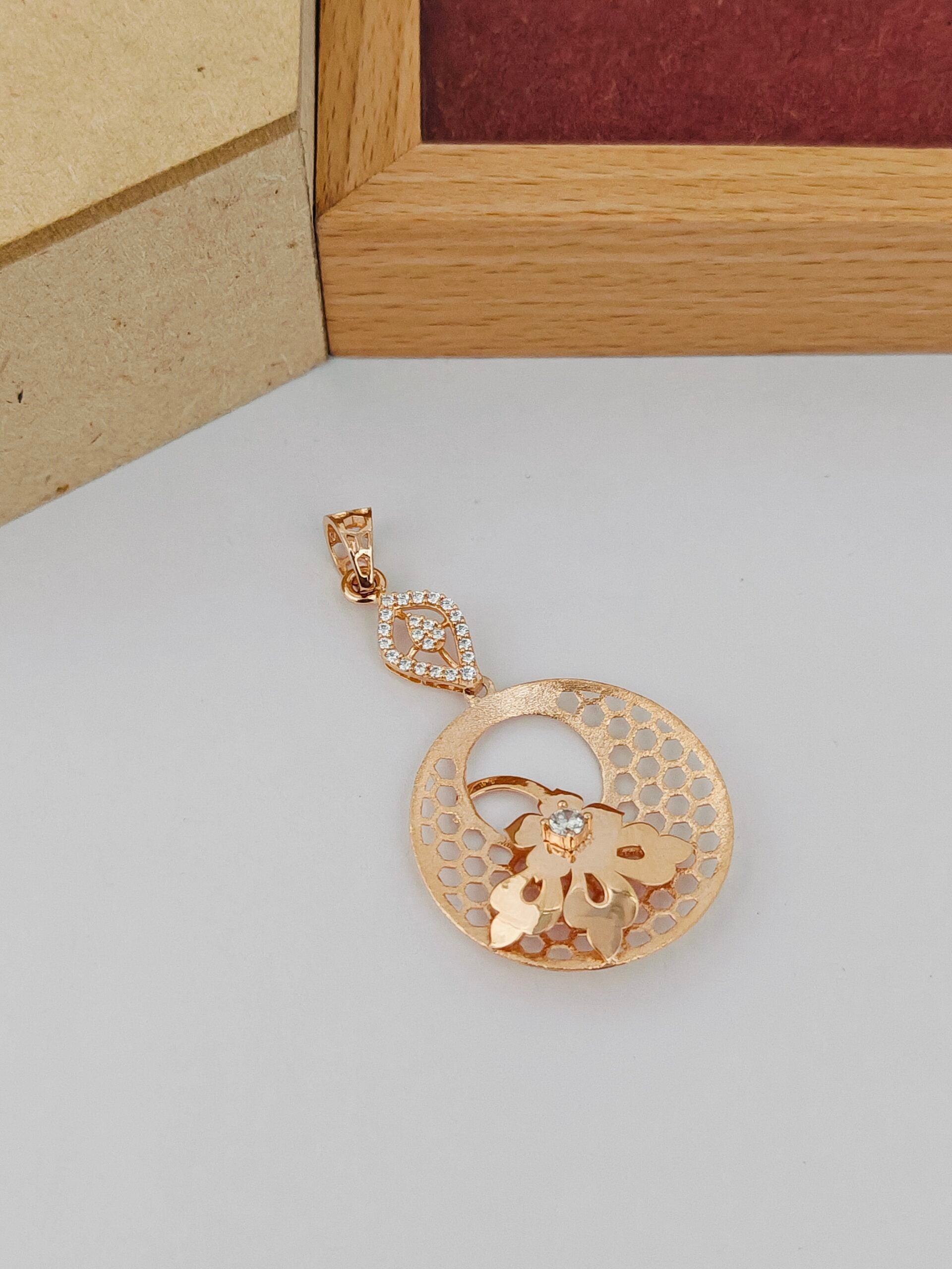 Gold pendant with floral design on a light gray surface