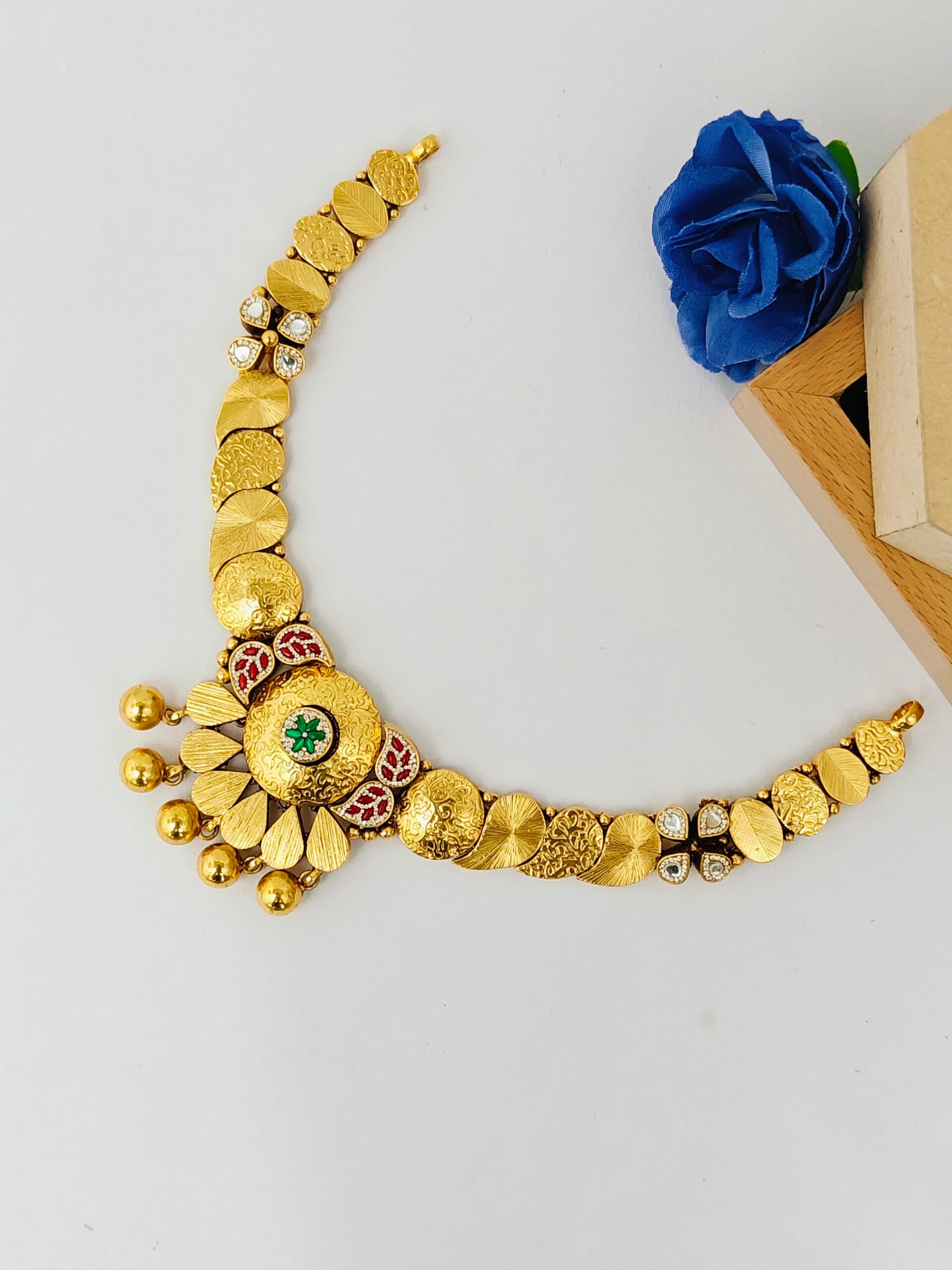 Gold necklace with decorative elements on a light gray background