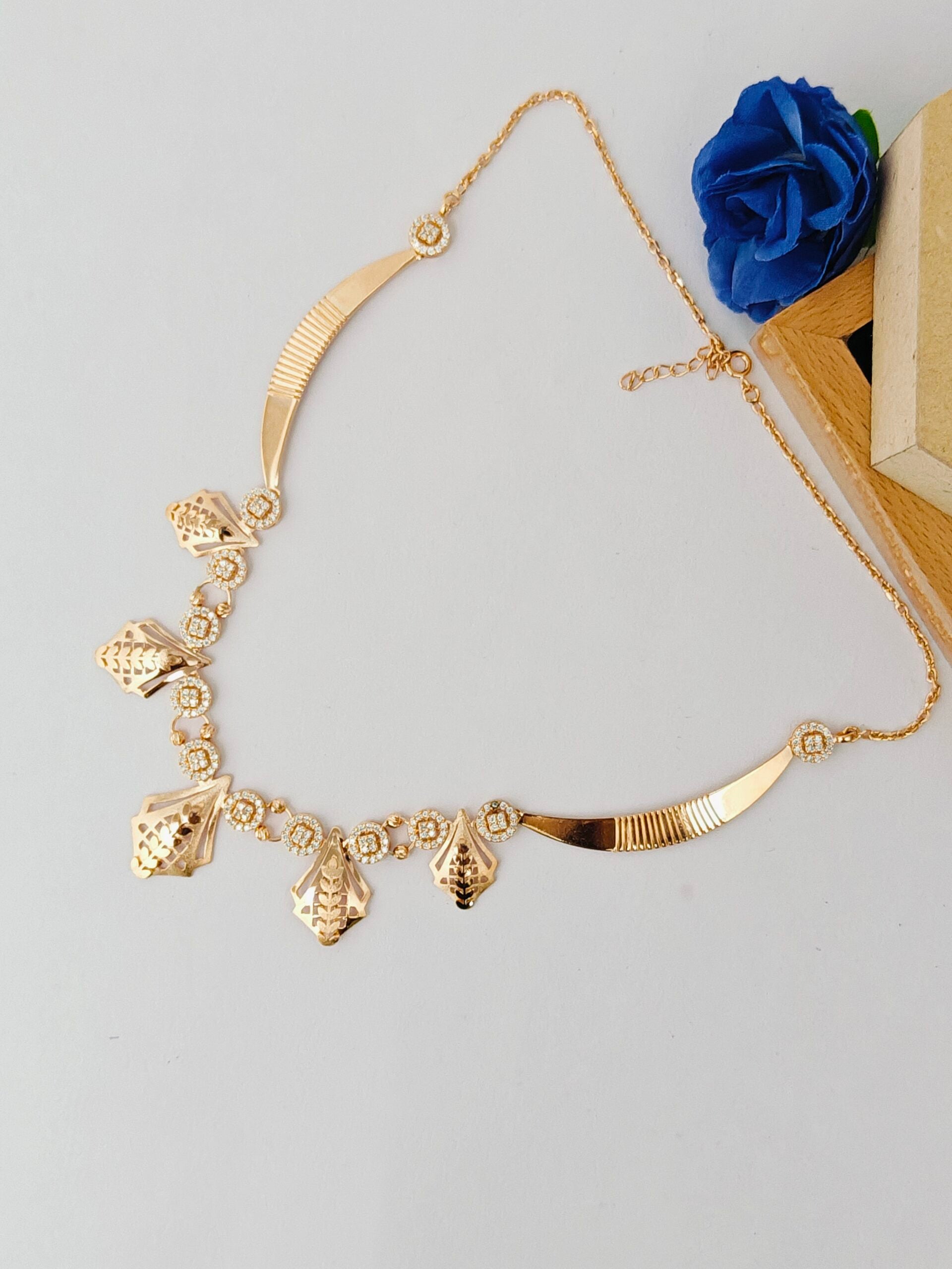 Gold necklace with decorative pendants on a light gray background