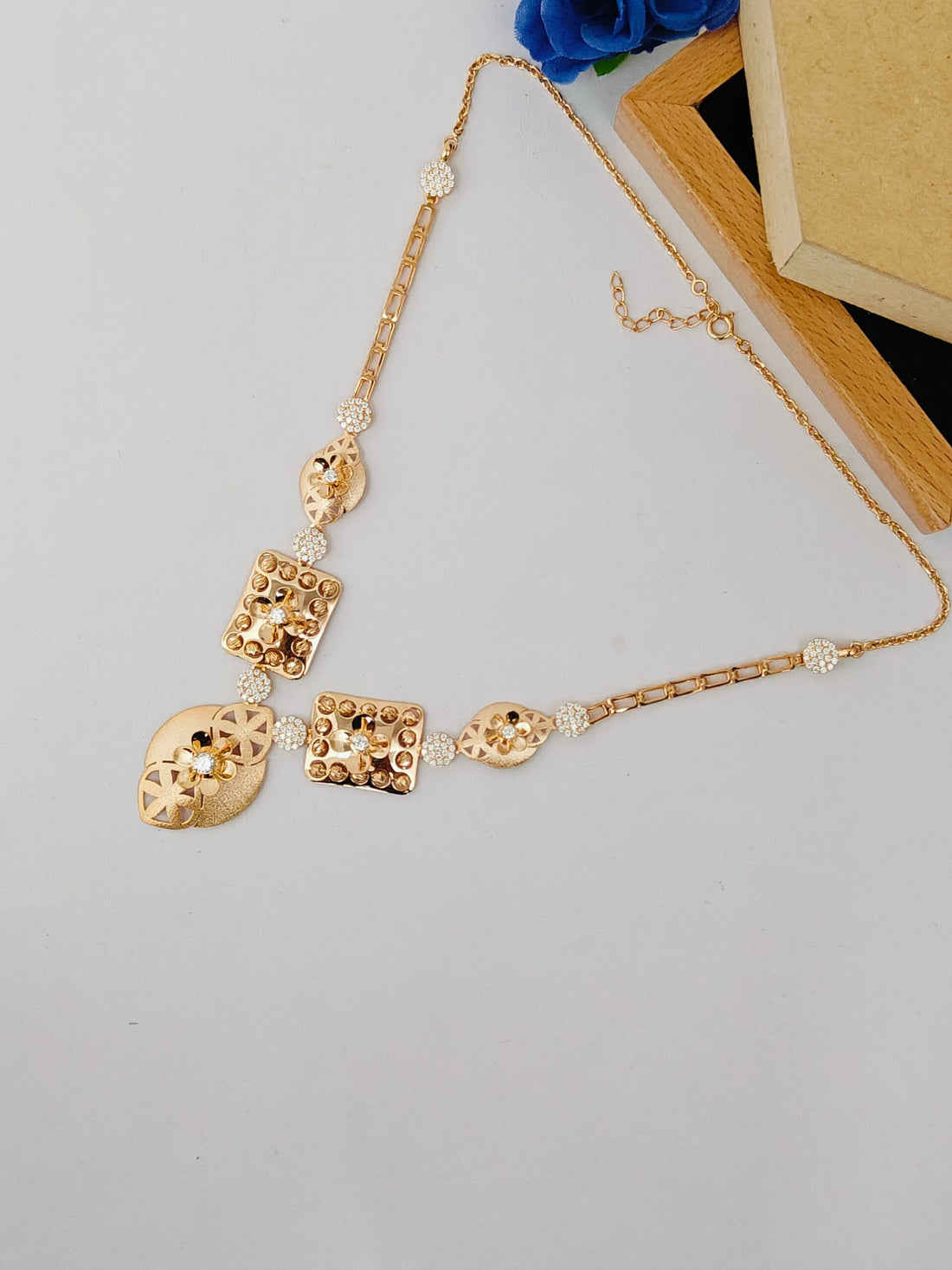 Gold necklace with decorative pendants on a light gray surface