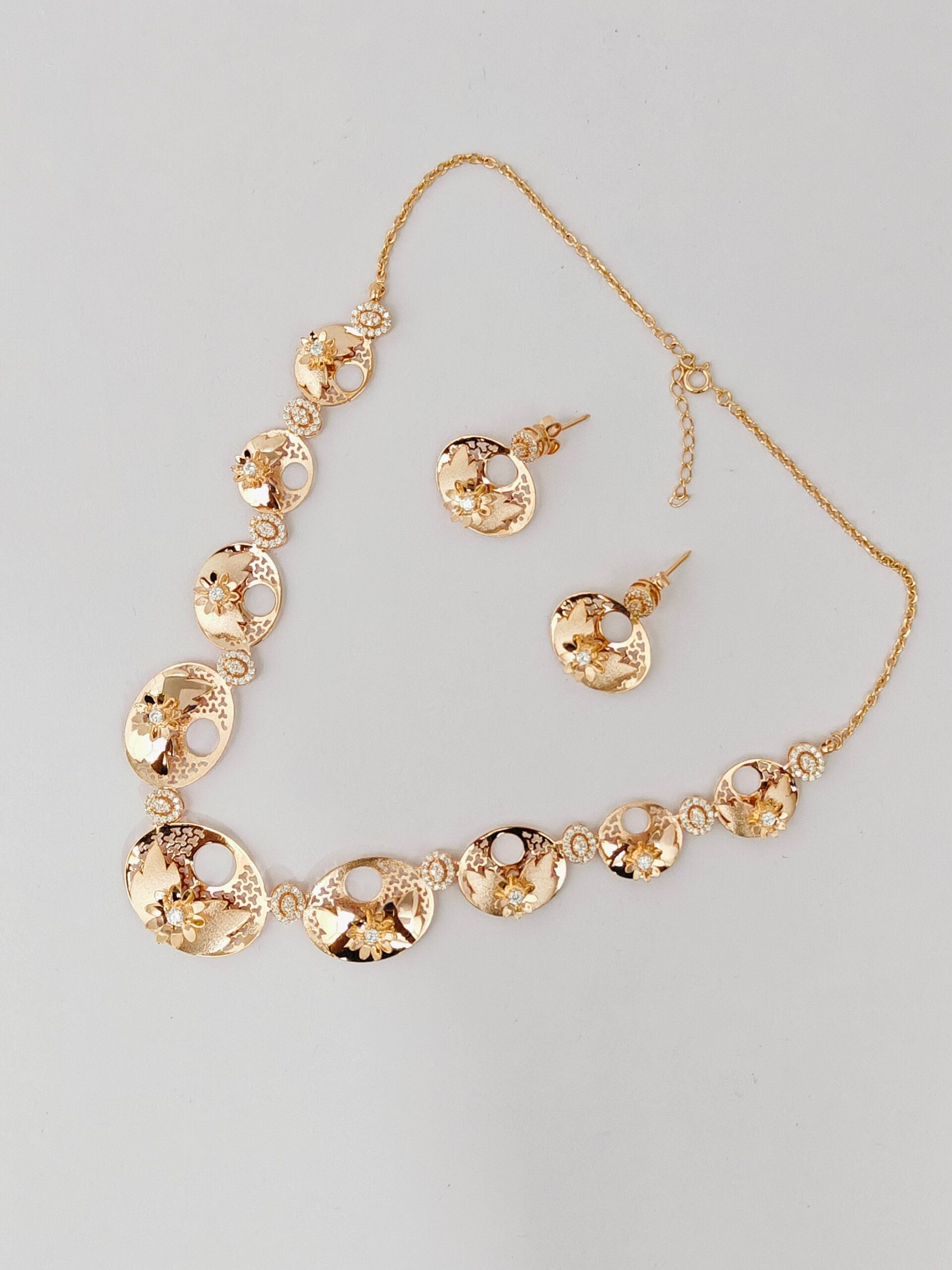Gold necklace and earrings set on a gray background